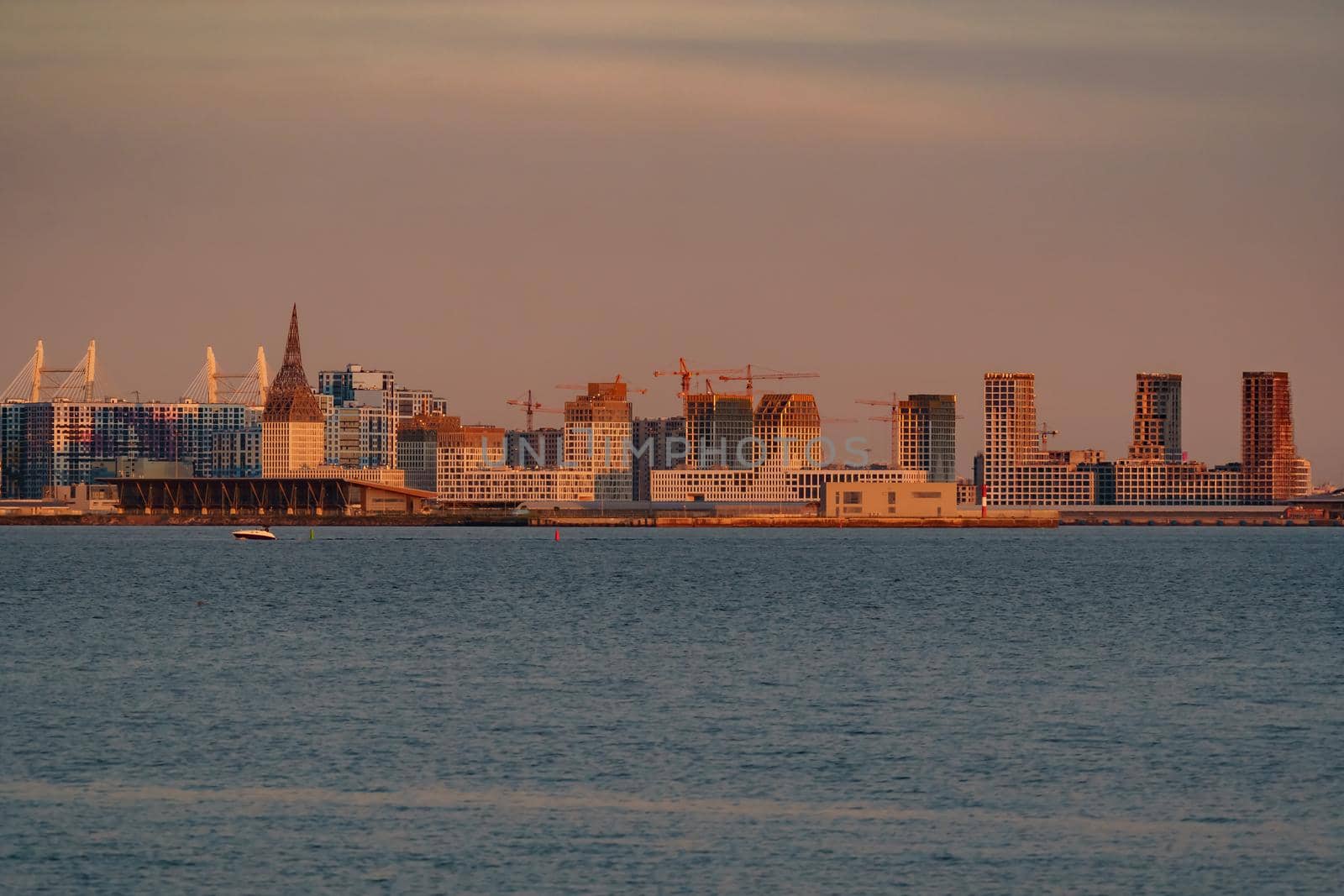 The residential complex under construction on the embankment of the Neva River on Vasilievsky island in sunset, bulk island, construction cranes. High quality photo