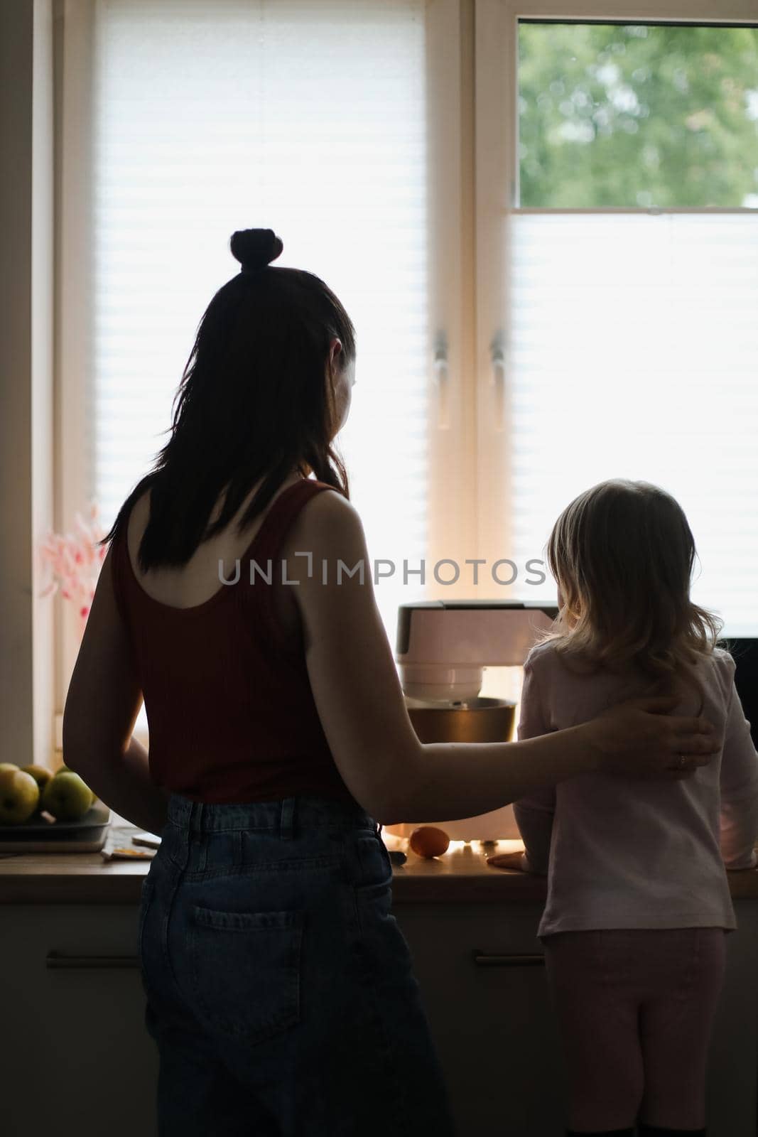 little girl helping her mother prepare a cake and cooking in the kitchen