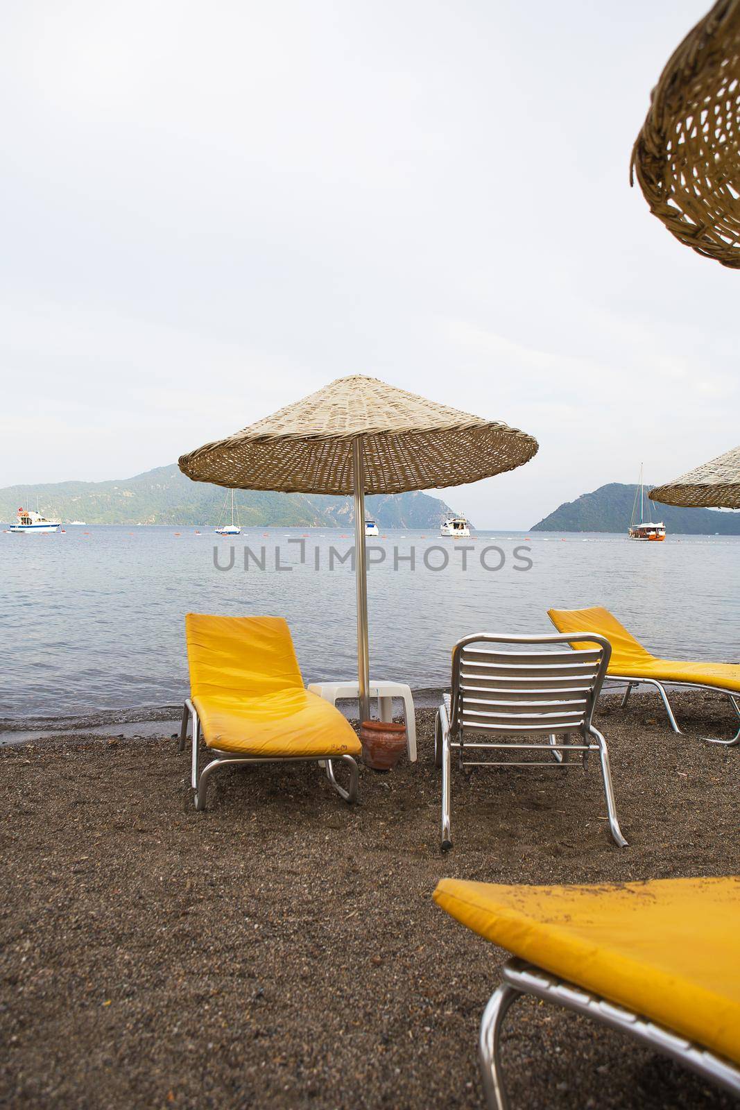 Beautiful yellow chaise lounges and umbrellas made from straw on the beach of Marmaris by sfinks