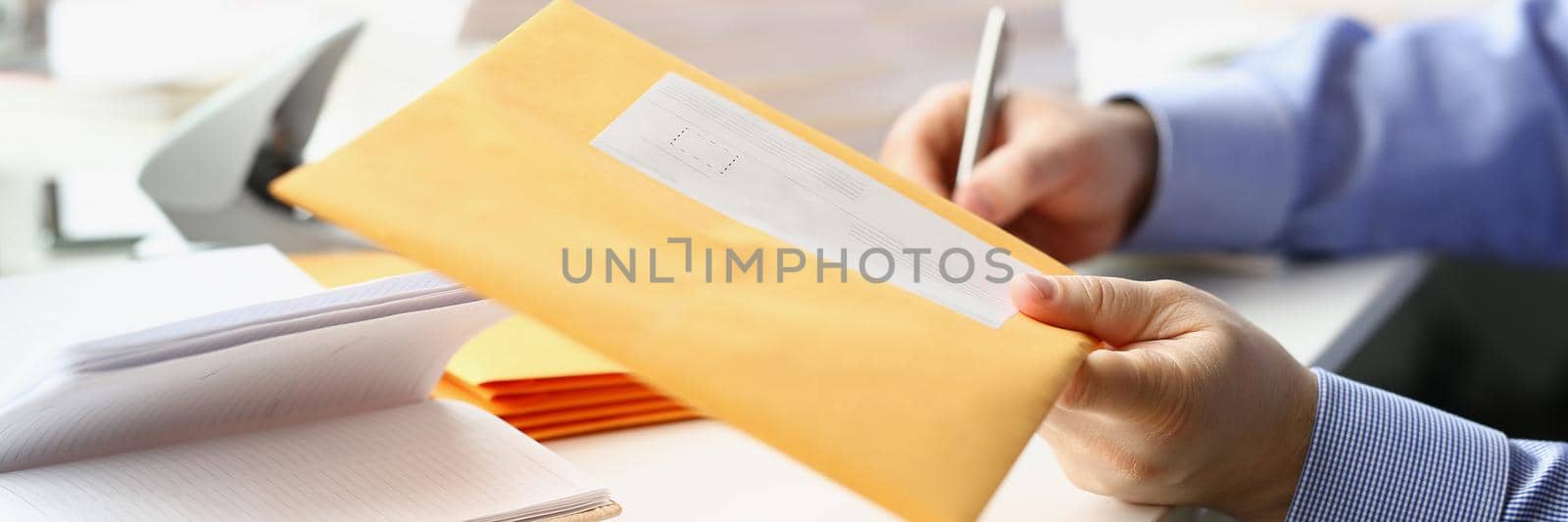 Close-up of businessman give envelope to courier for further delivery to address. Write address on every package with documents. Delivery service concept