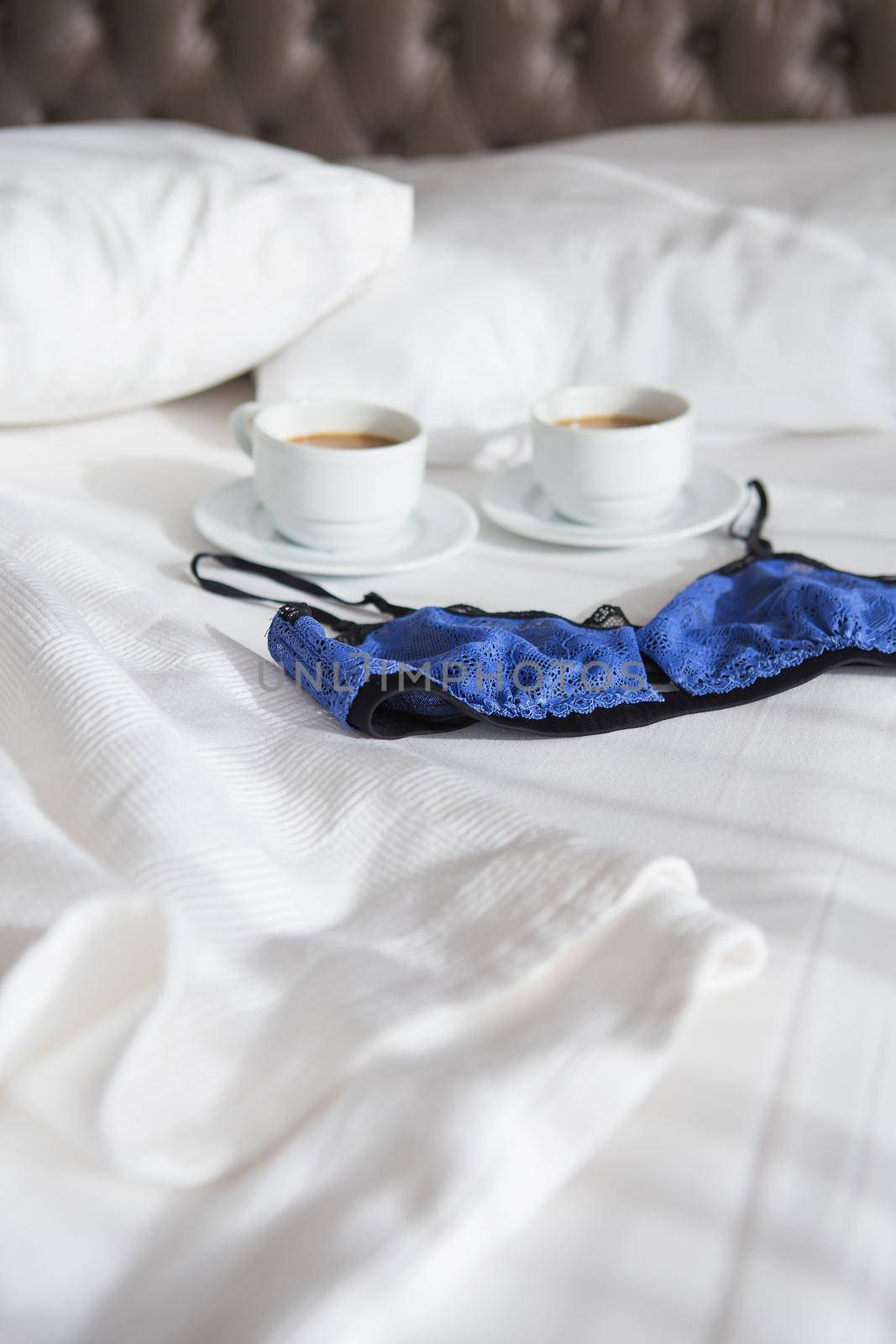 two cups of coffee and a beautiful bra on a white bed, close-up by sfinks