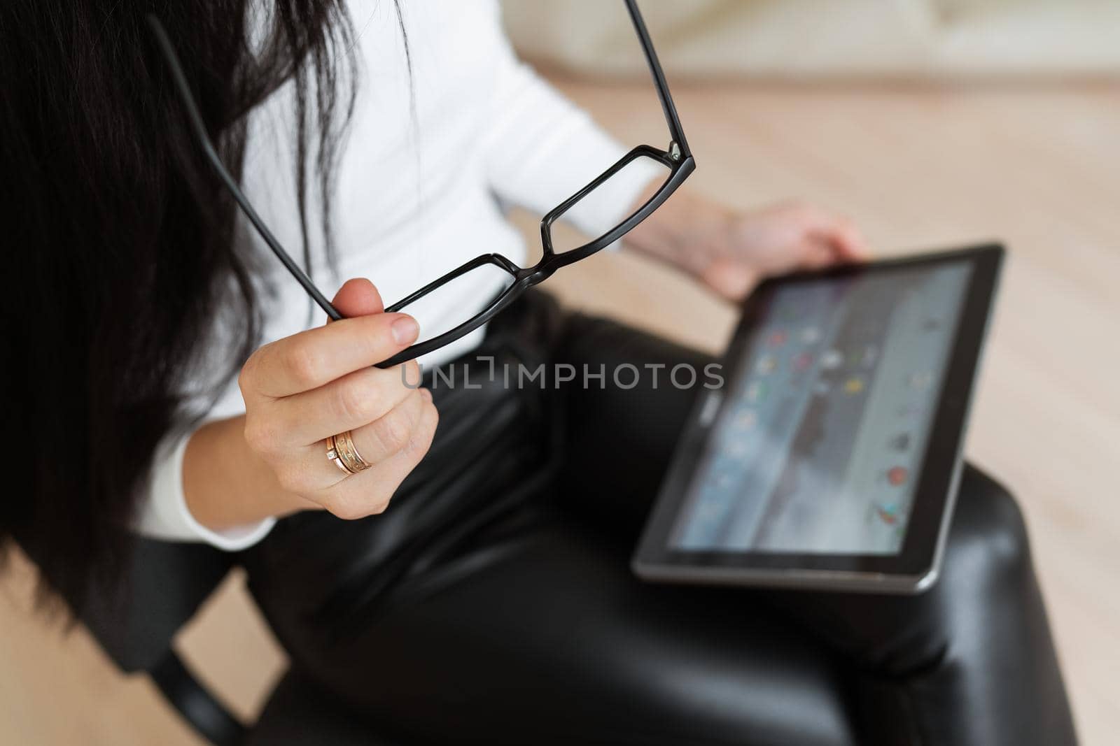 A business woman holds glasses and a tablet in her hands and works outside the office, remote robot. Modern technologies and business. by sfinks