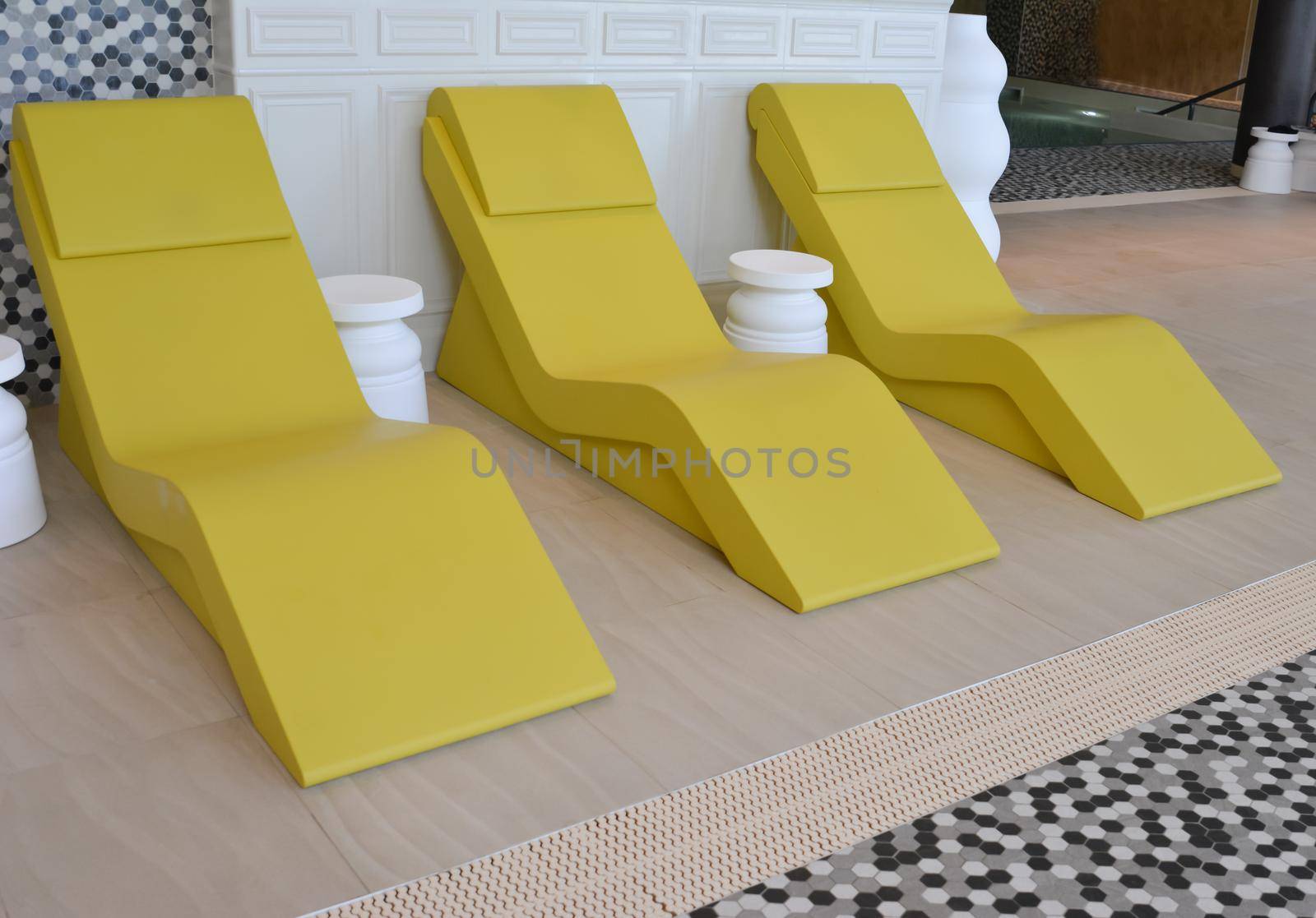 line of three yellow chaise longue in the pool