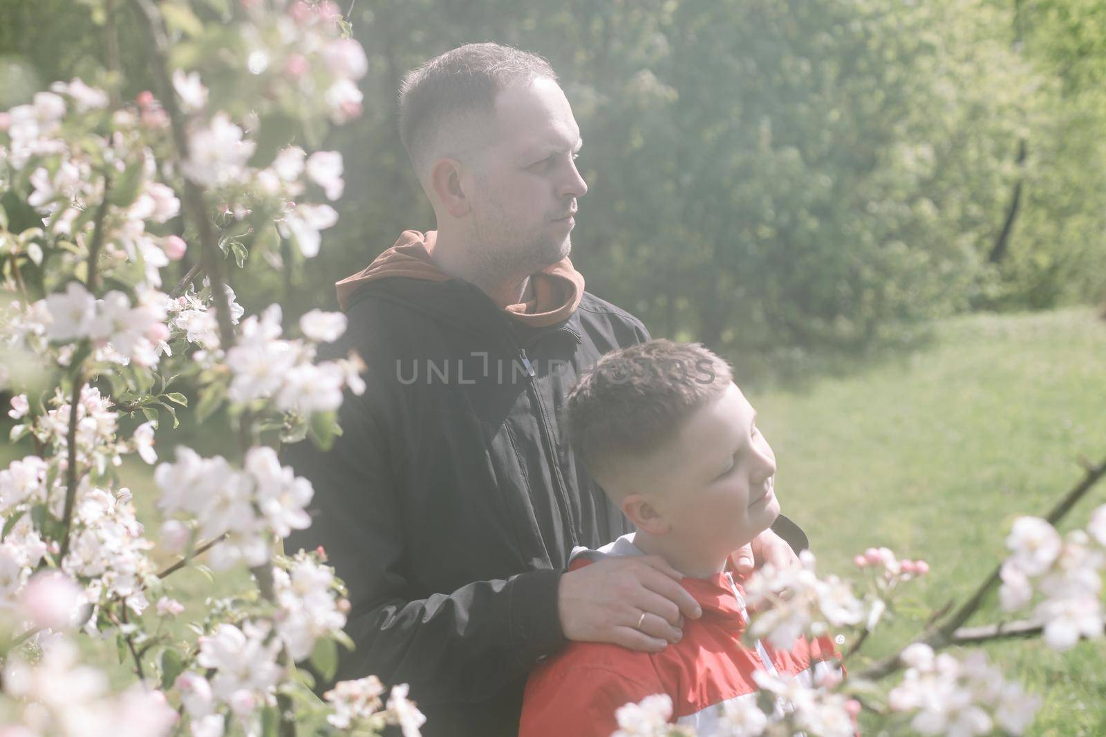 Teenager boy with father together in park in spring.