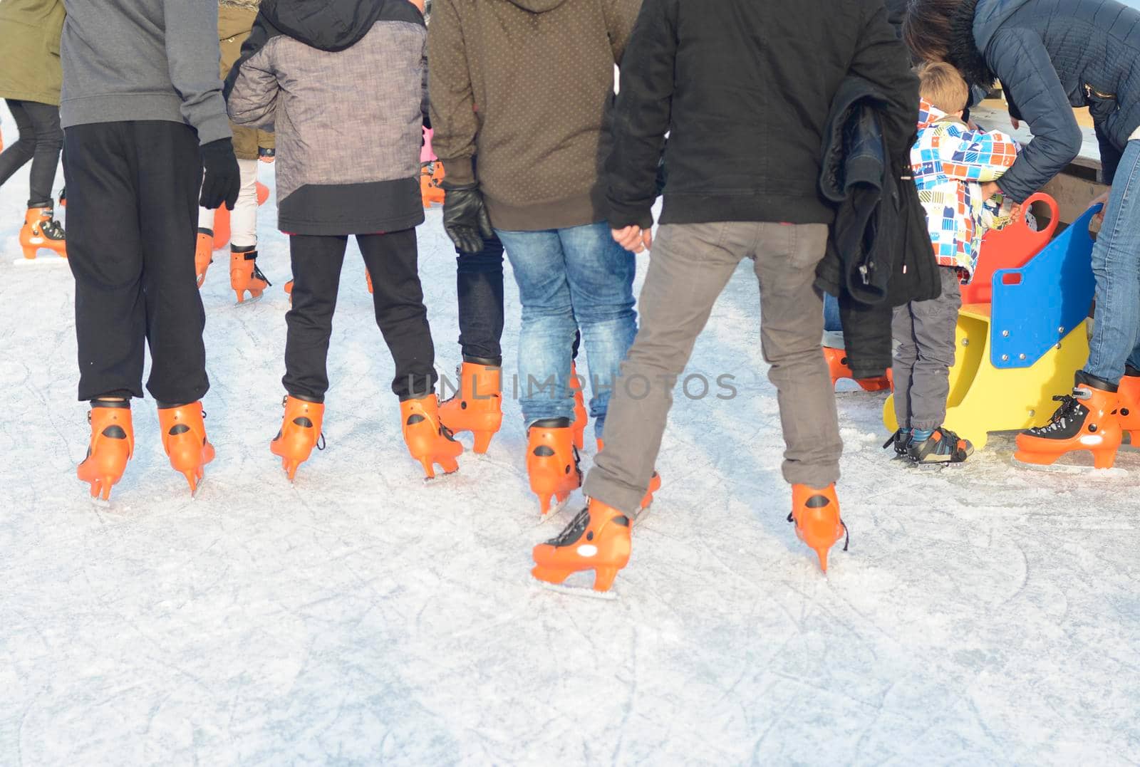 Ice skating teenagers on the skating rink in orange ice skates.