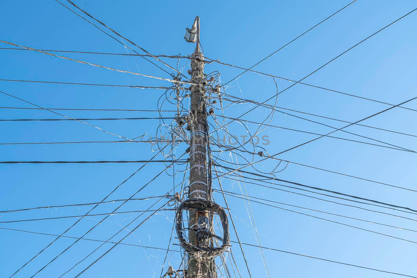 a web of wires on a pole against the sky. Photo