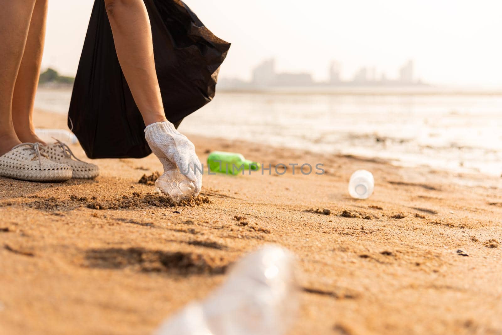 Volunteer woman picking plastic bottle into trash plastic bag black for cleaning the beach, female clean up garbage, Ecology concept and World Environment Day, Save earth concept