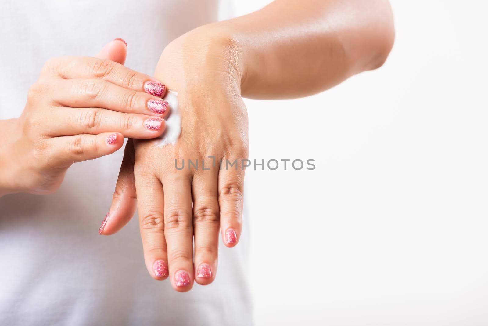 Woman applying lotion cosmetic moisturizer cream on her behind the palm skin hand by Sorapop