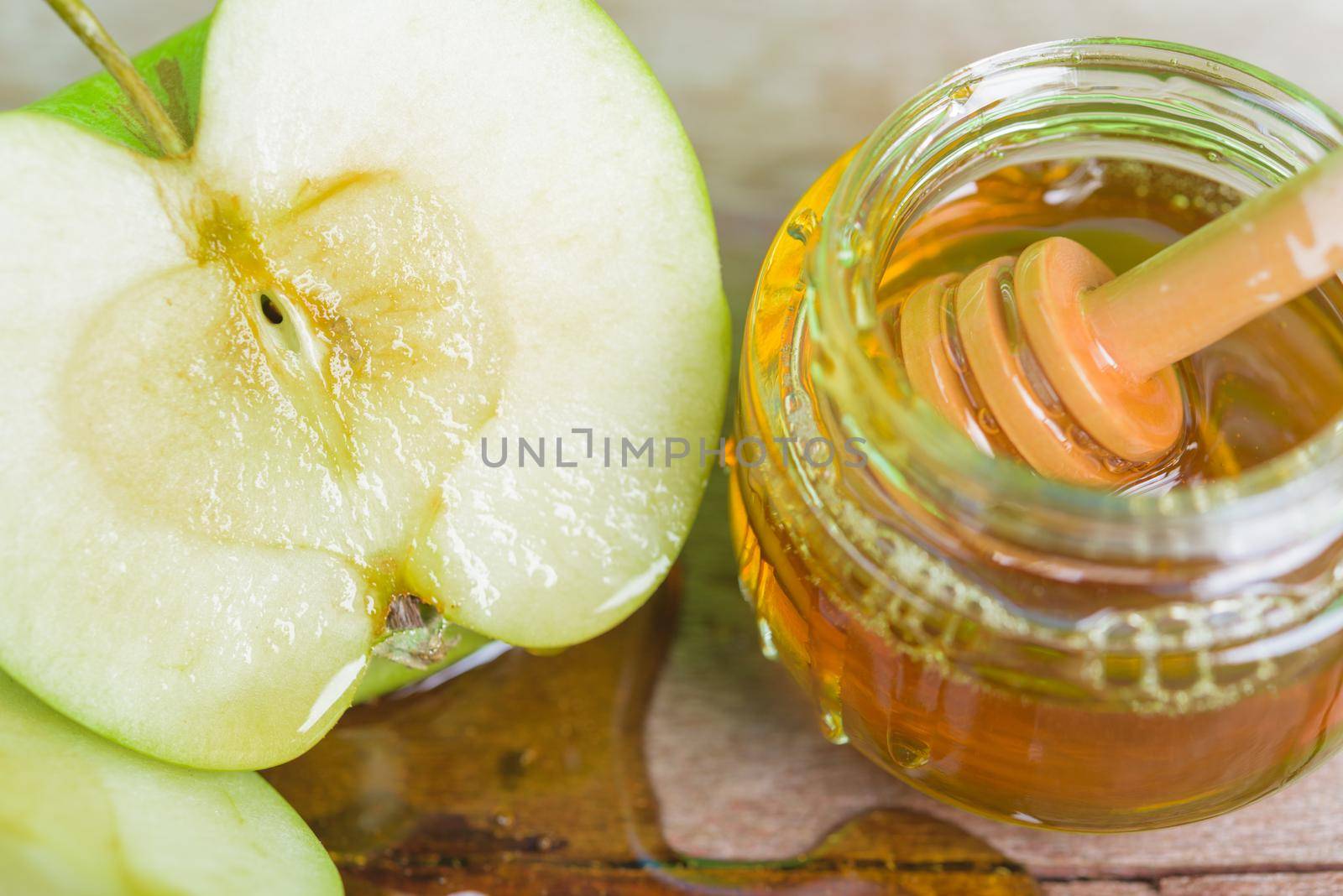 Jewish holiday, Apple Rosh Hashanah, on the photo is top view have honey in jar and drop honey already on green apples on wooden with green background