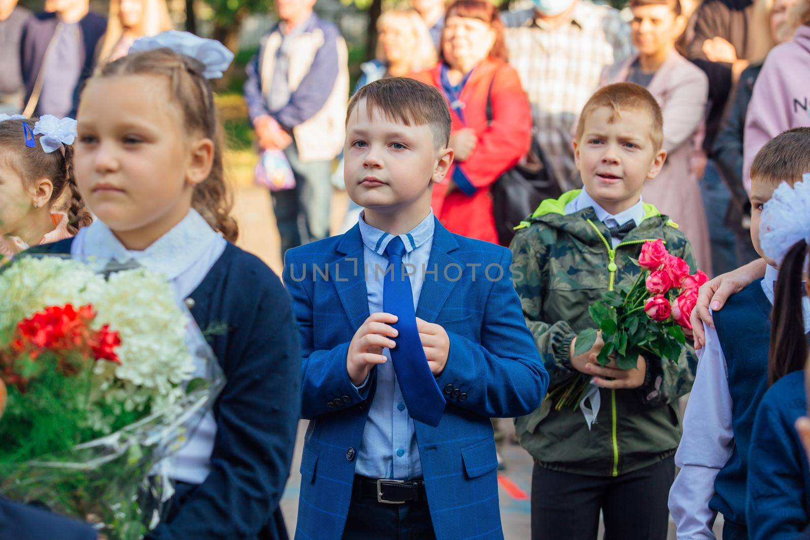 NOVOKUZNETSK, KEMEROVO REGION, RUSSIA - SEP, 1, 2021: Meeting with the first-grade pupils and teacher at schoolyard. The day of knowledge in Russia.