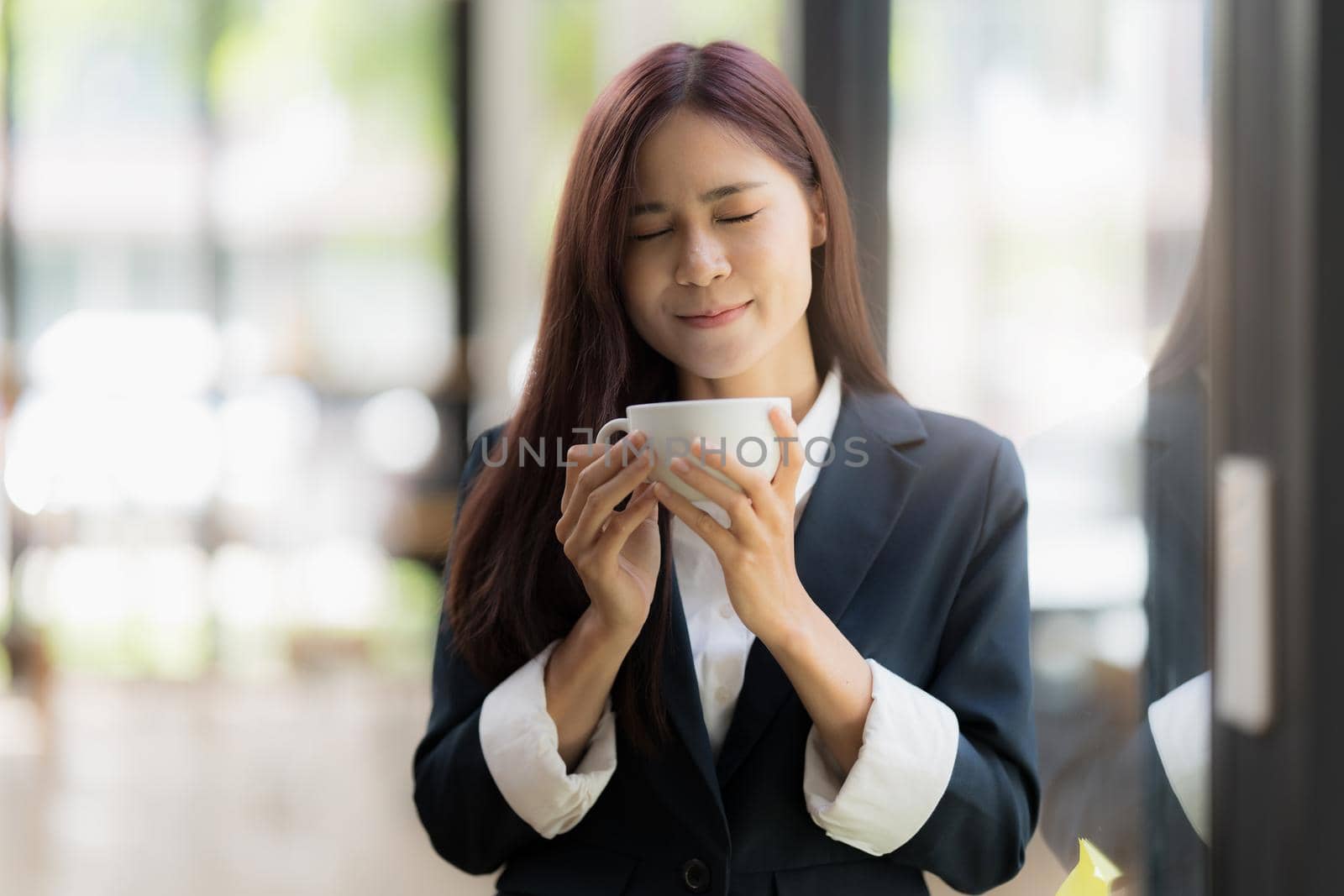 A portrait of Asian happy Businesswoman smiling and drinking coffee