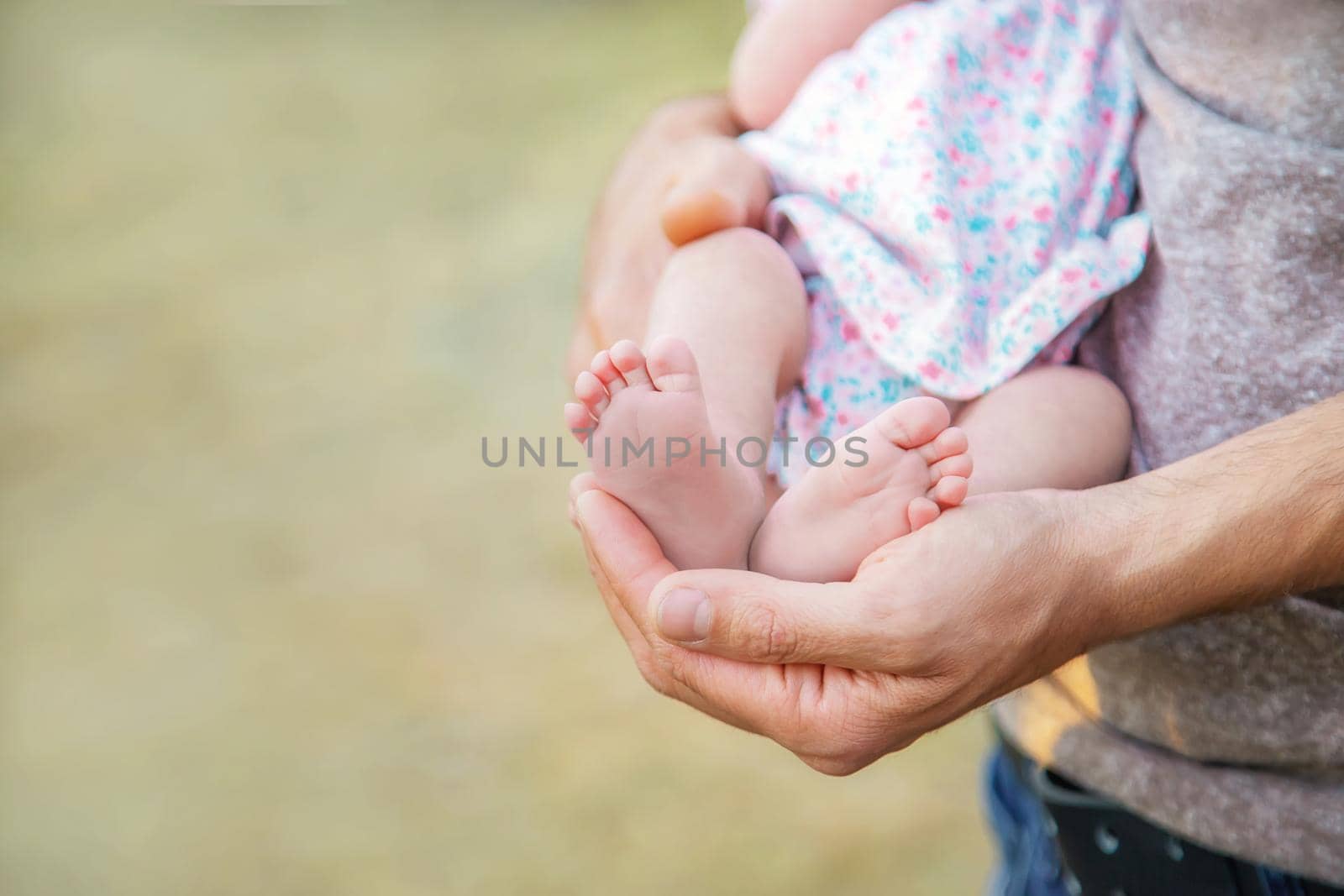 Feet of a newborn baby in the hands of a father. Selective focus. People.