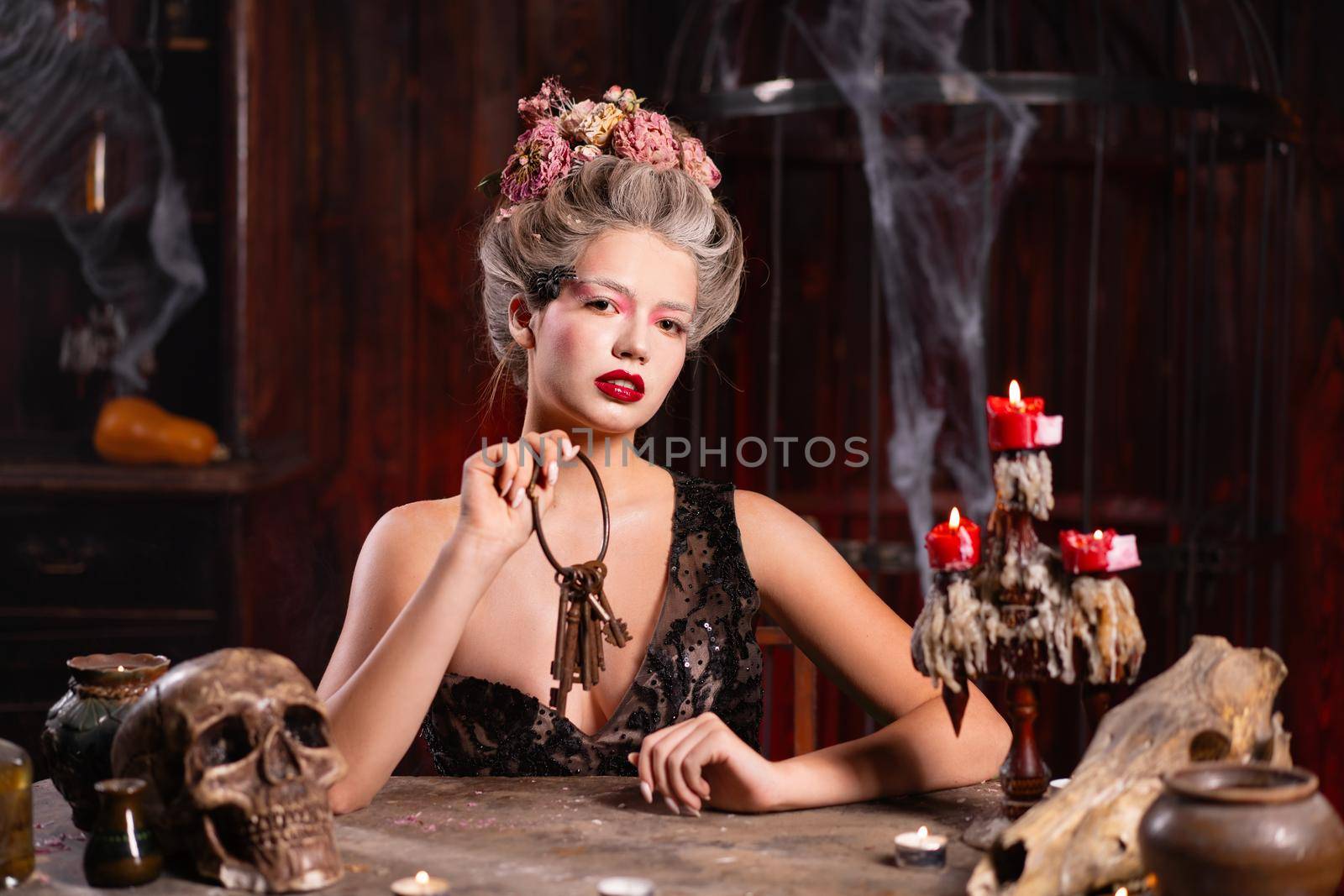 Portrait fortune teller woman reading future on magical scull. Magic and divination. Young beautiful enchanted female witch sitting on the table waiting your desire. Scary Halloween atmosphere