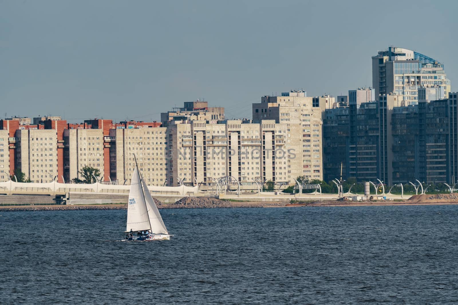 Russia, St. Petersburg, 10 June 2022: The residential complex under construction on the embankment of the Neva River on Vasilievsky island in sunny day, construction cranes, sailing yachts. High quality photo