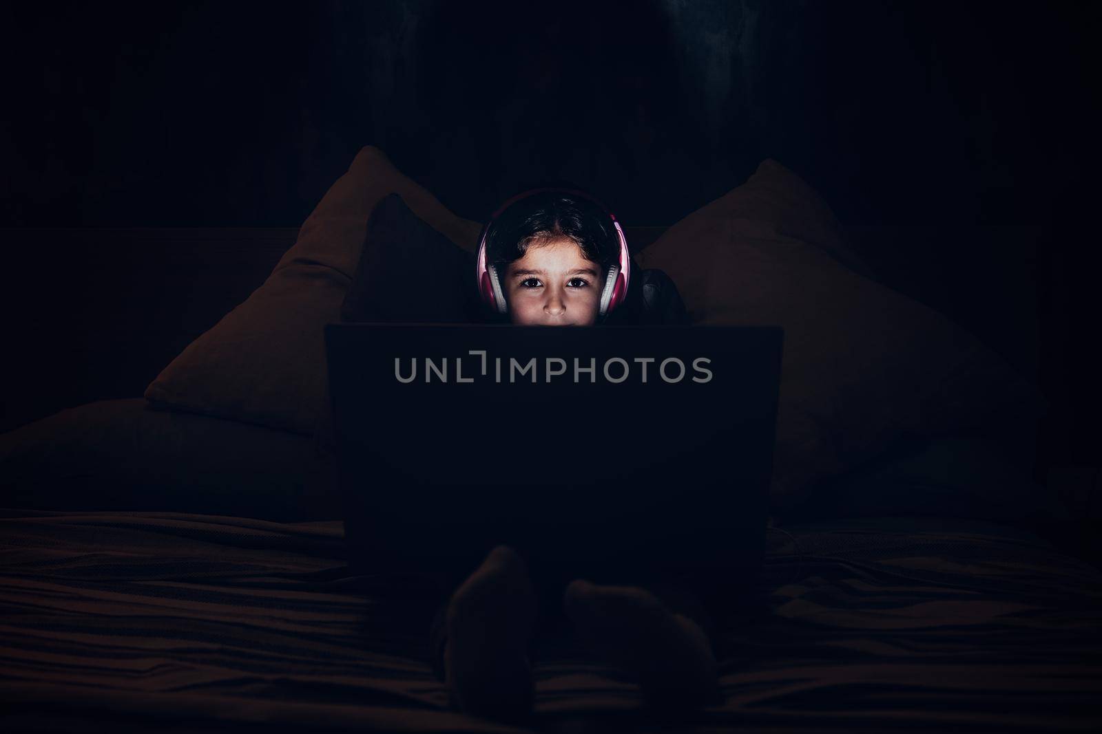 little girl with a computer in the darkness at bed by raulmelldo