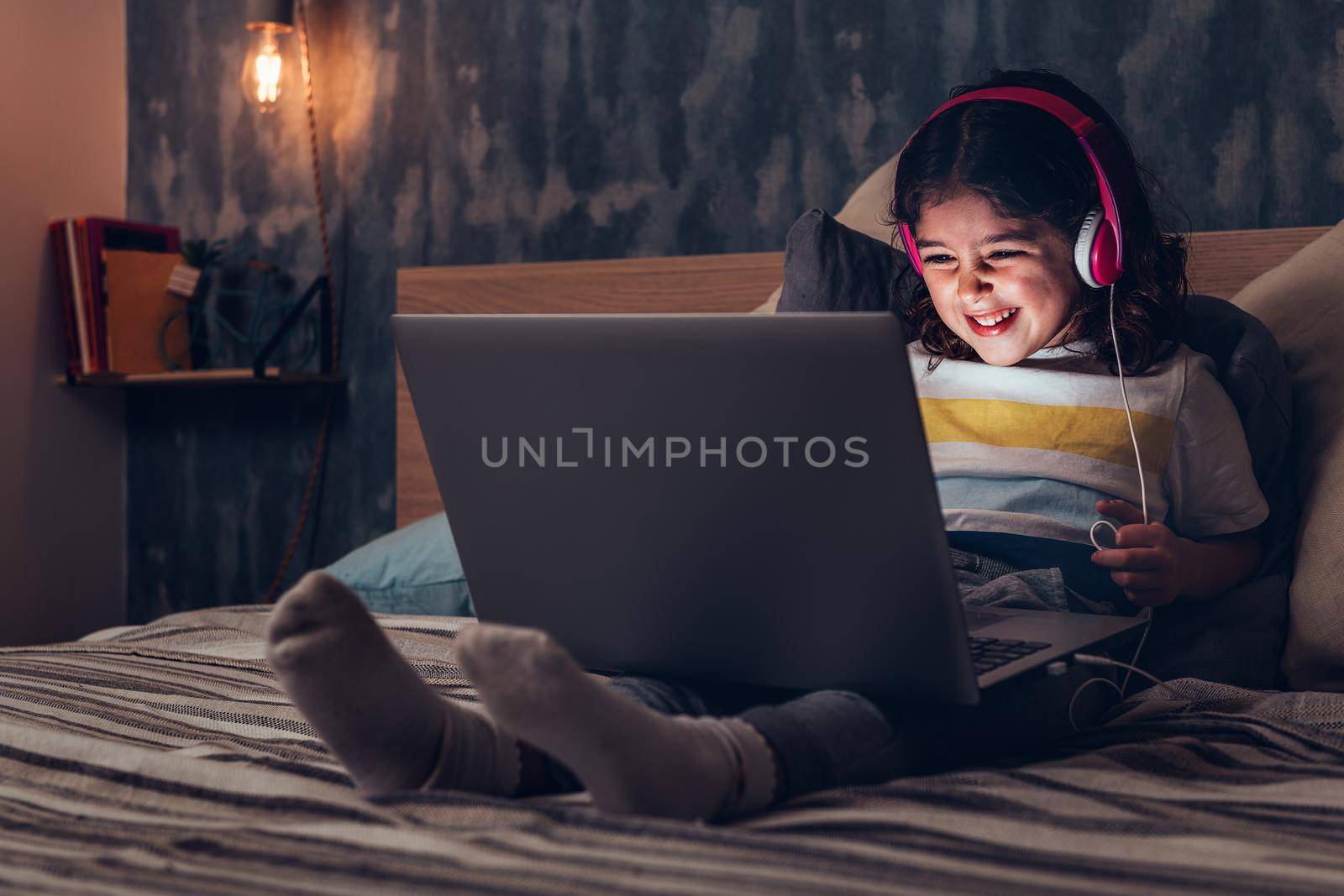 little girl smiling with a laptop in the darkness by raulmelldo