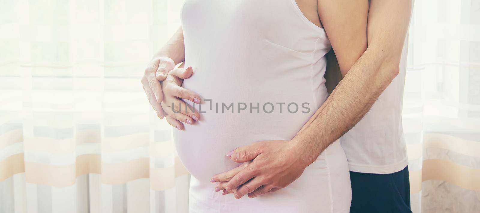 A pregnant woman and a father of a child hug a belly. Selective focus. by yanadjana