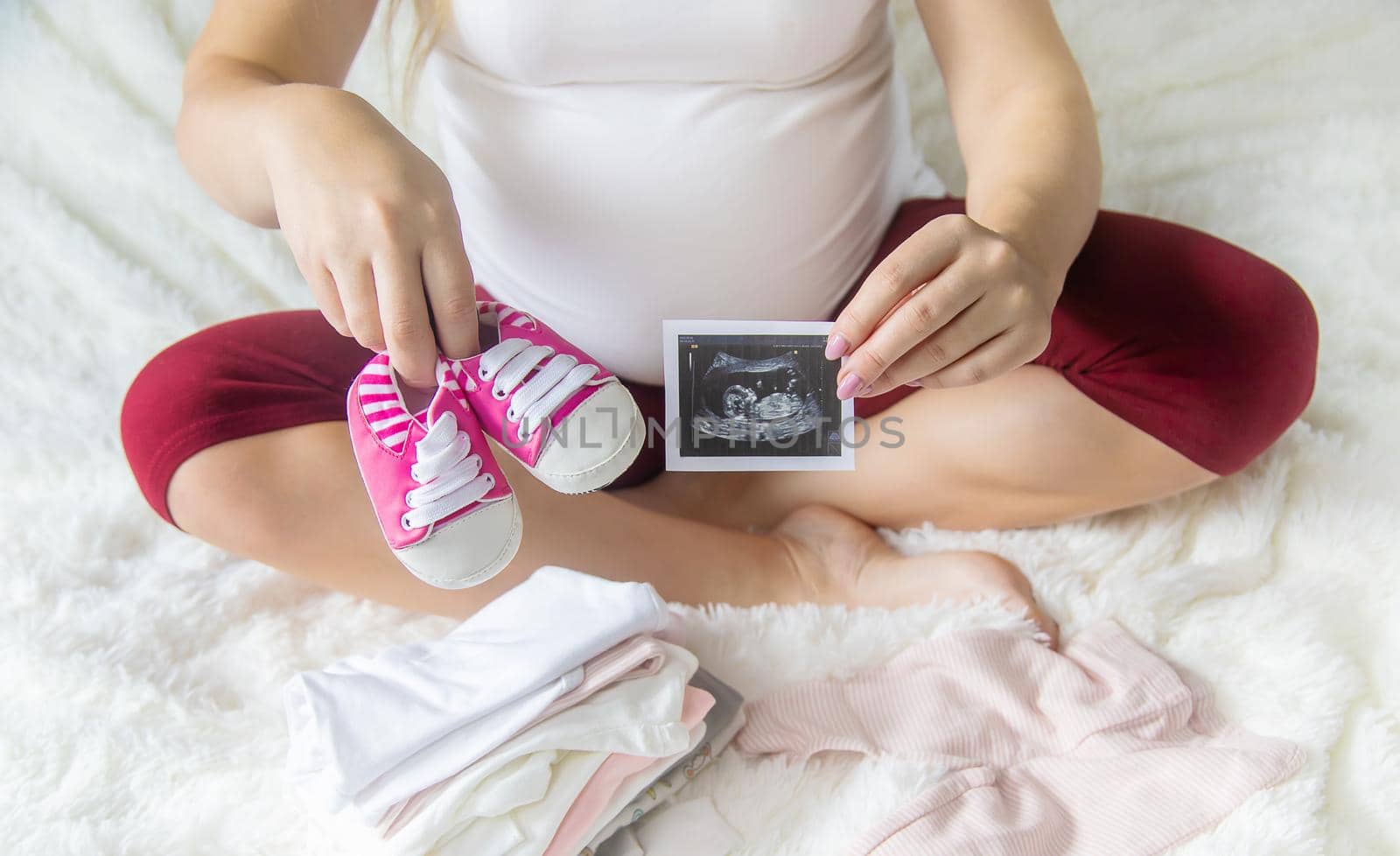 A pregnant woman holds a snapshot of an ultrasound in her hands. Selective Focus. people.