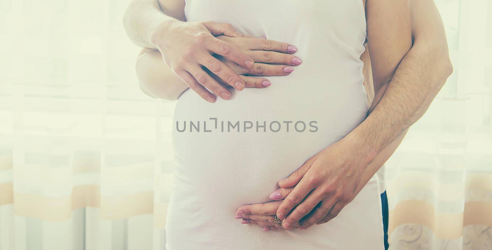 A pregnant woman and a father of a child hug a belly. Selective focus. NATURE.