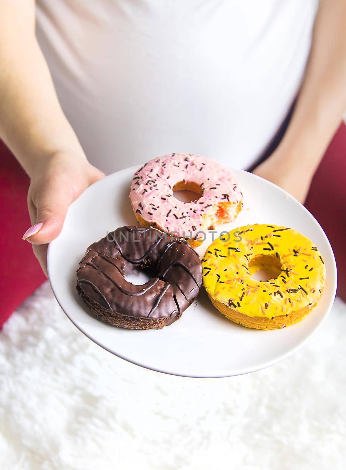 A pregnant woman eats sweet donuts. Selective Focus. Food.