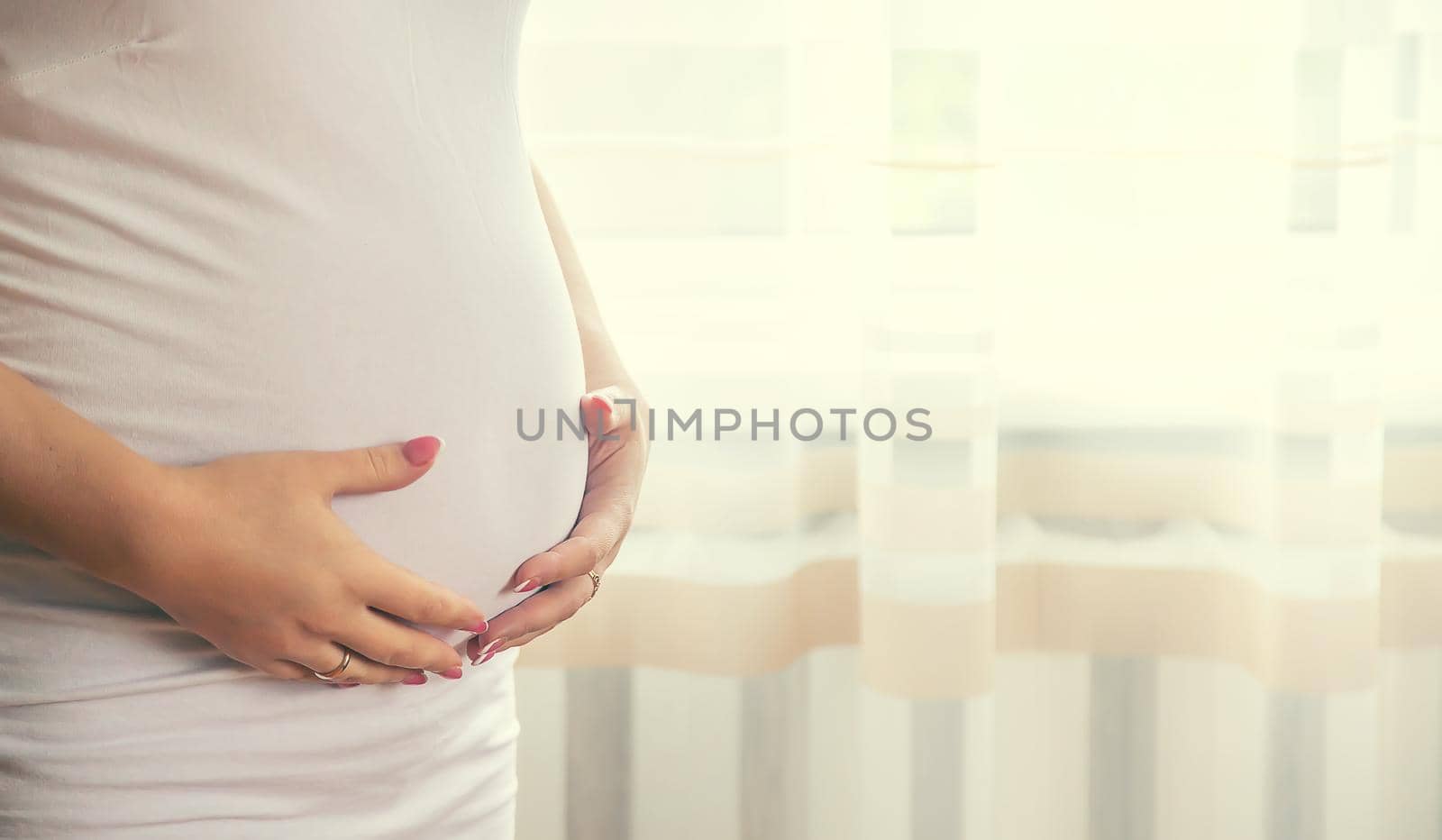 A pregnant woman hugs her belly. Selective focus. People.