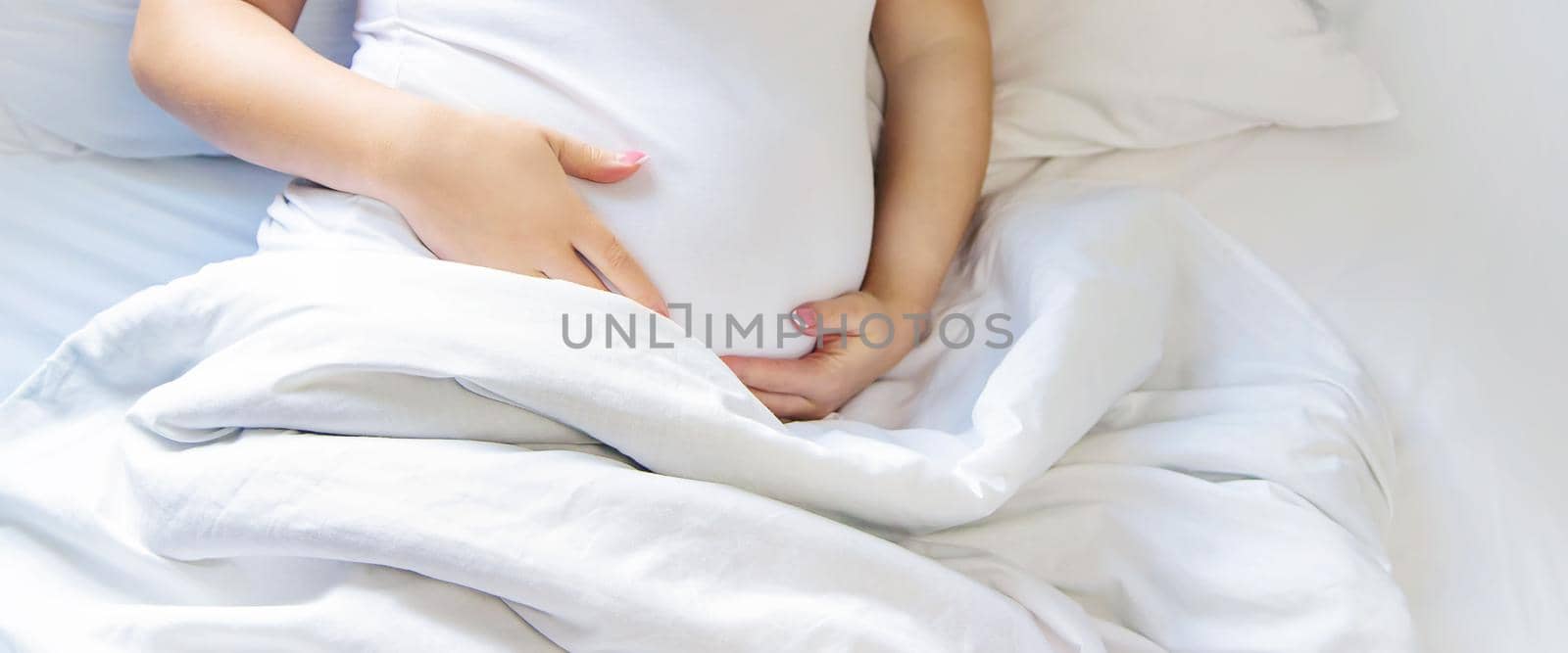 A pregnant woman hugs her belly. Selective focus. People.