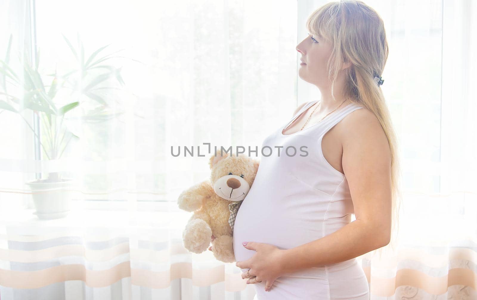 A pregnant woman with a toy hugs her stomach. Selective focus. People.