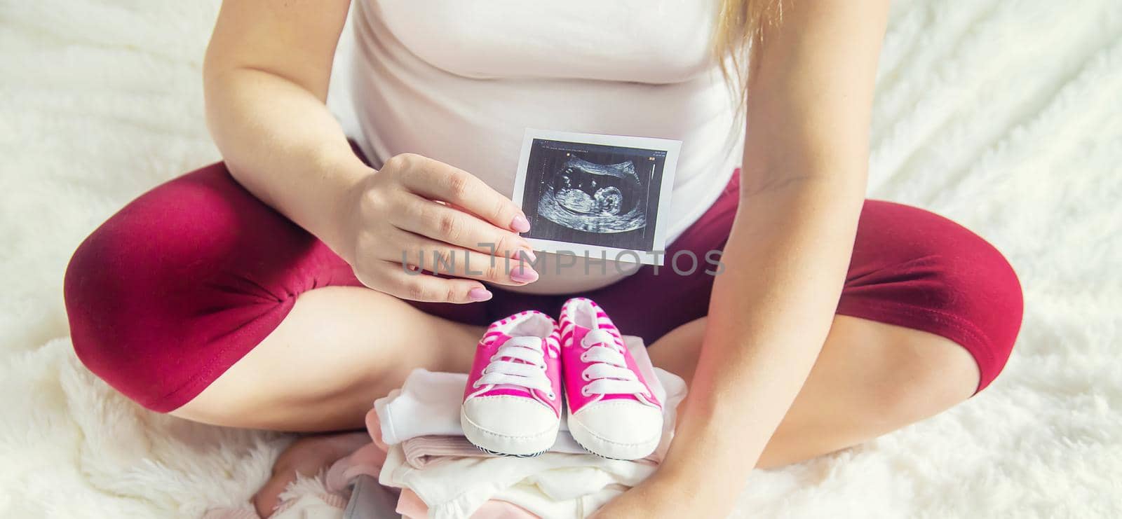 A pregnant woman holds a snapshot of an ultrasound in her hands. Selective Focus. by yanadjana