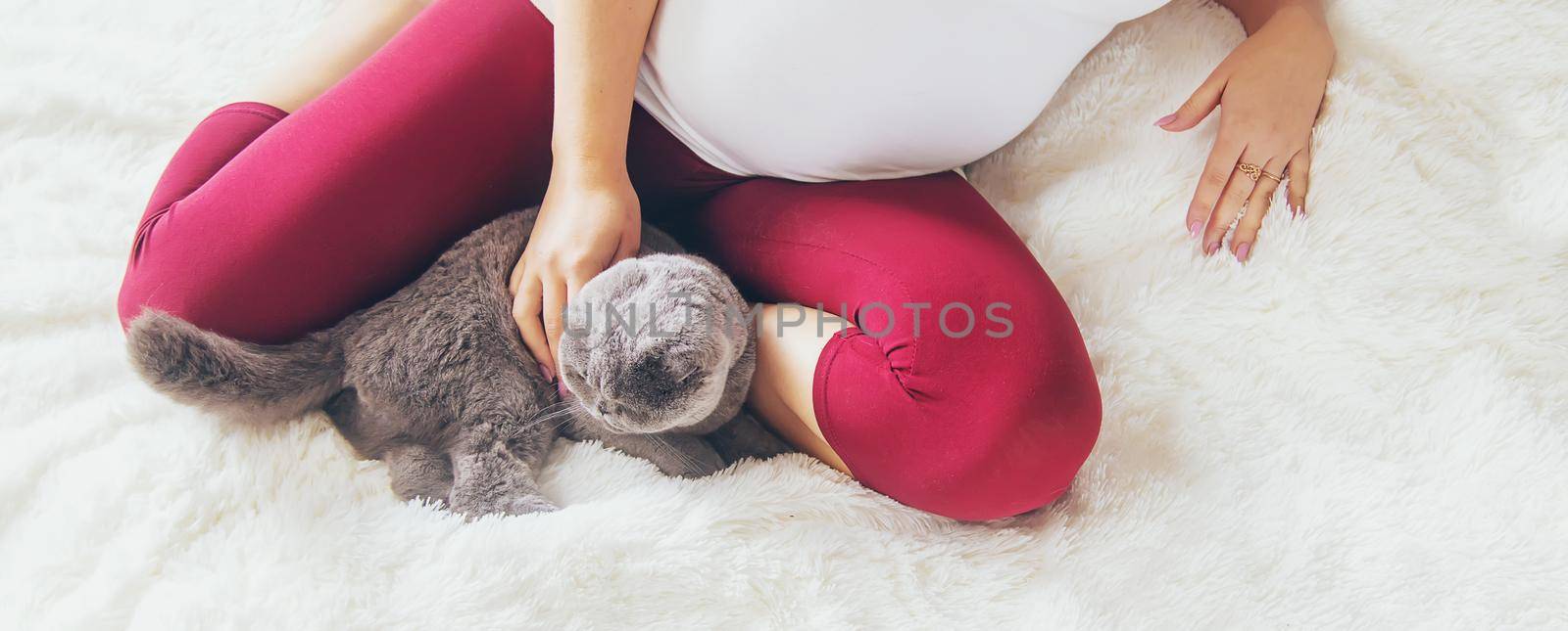 A pregnant woman with a cat lies in bed. Selective focus. animal.