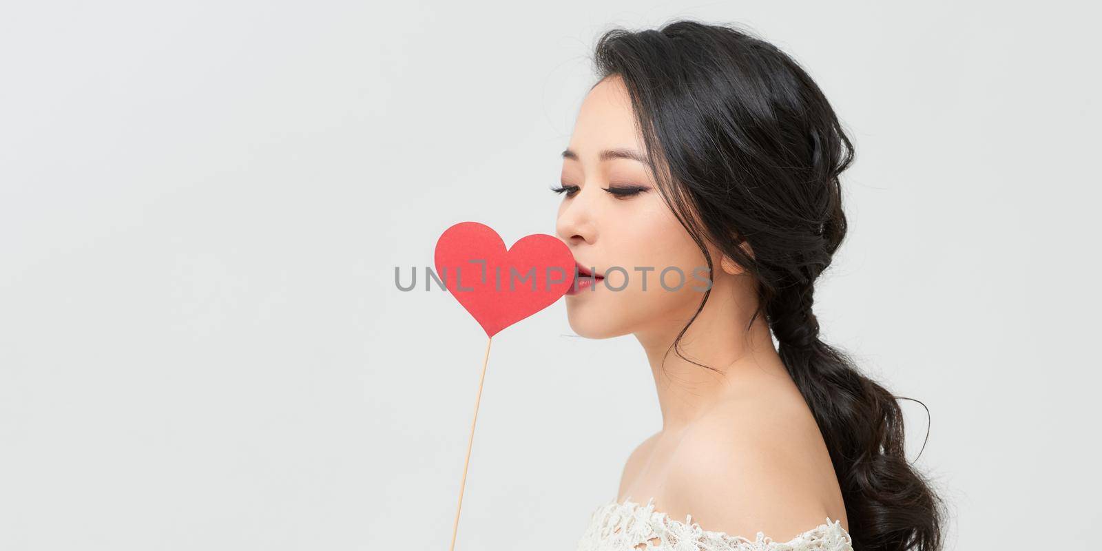 Portrait of pretty girl holding red paper heart on stick