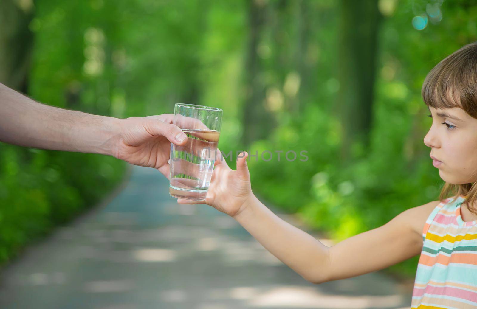 The father gives the child a glass of fresh water. Selective focus. nature.