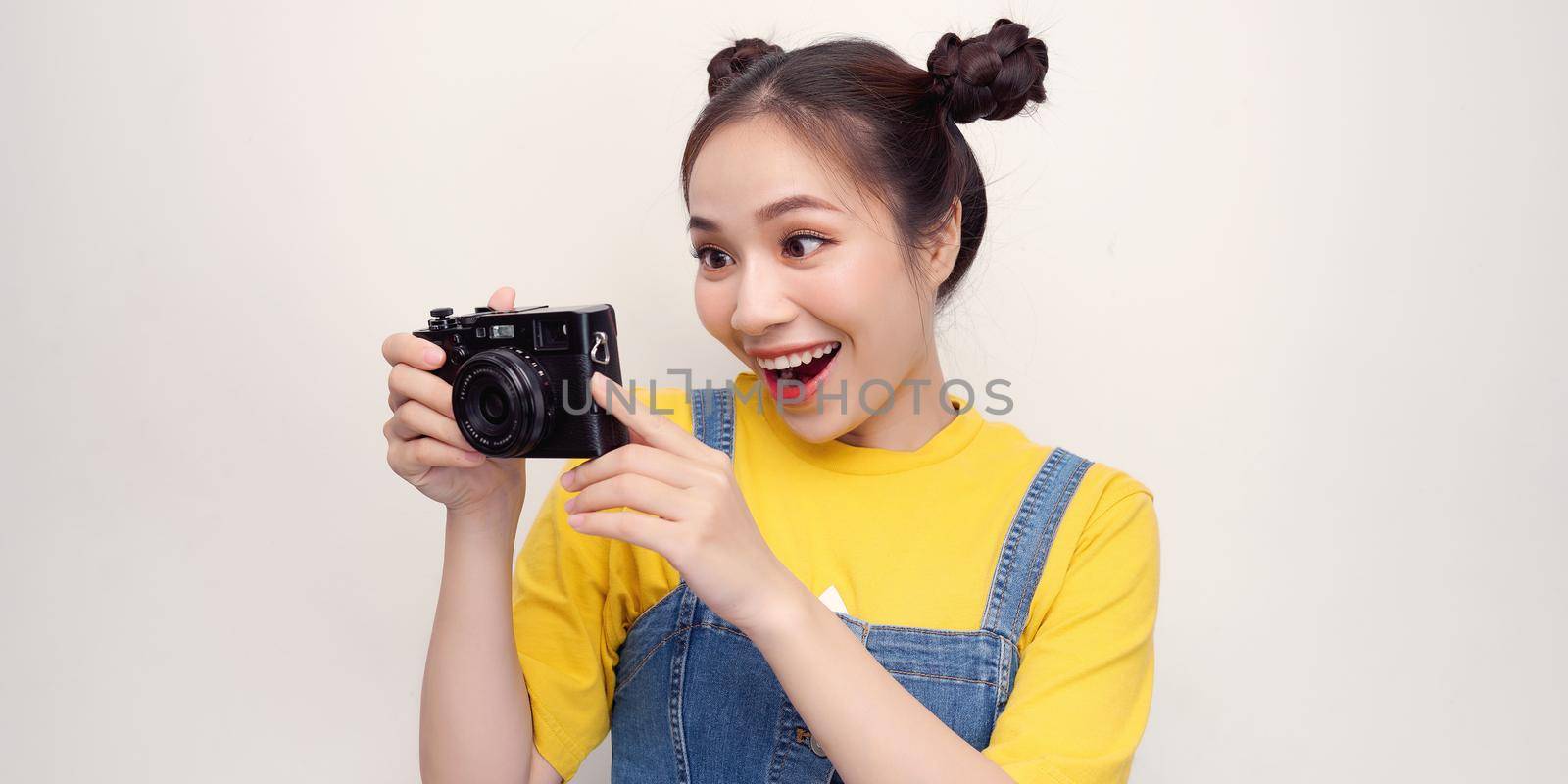 Beautiful young woman taking photo with digital camera, against white background.