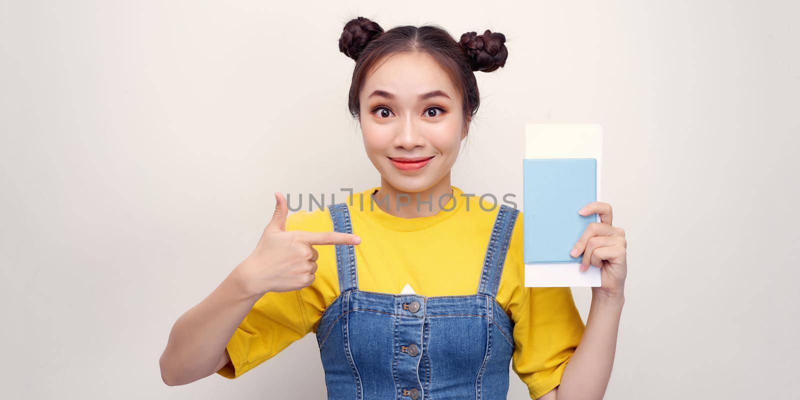 Young beautiful asian tourist woman on vacation holding passport pointing with fingers, excellent symbol