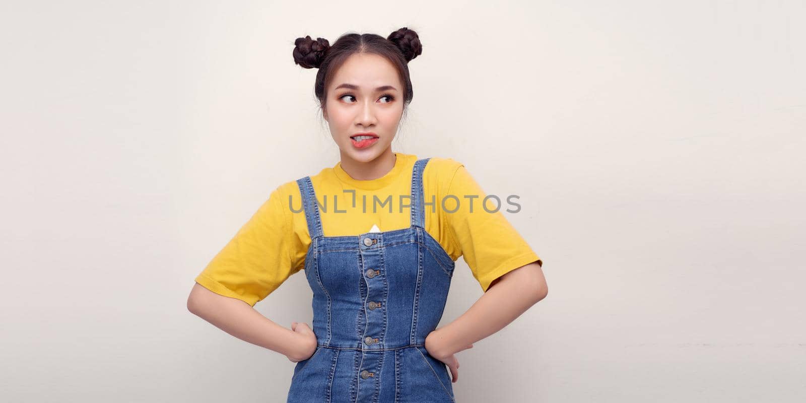 Smiling pretty young woman girl in casual denim clothes posing isolated on white wall background. Standing with arms akimbo on waist