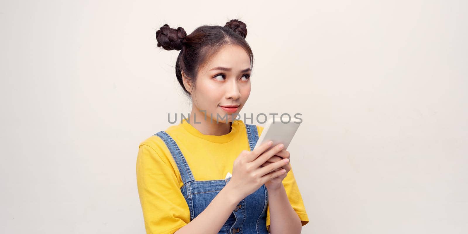 Excited beautiful woman receiving SMS in mobile phone over plain background by makidotvn