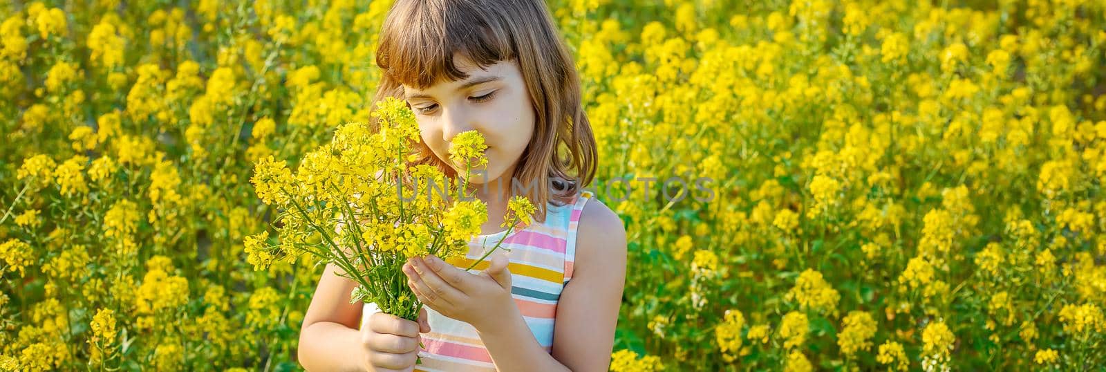 A child in a yellow field, mustard blooms. Selective focus..