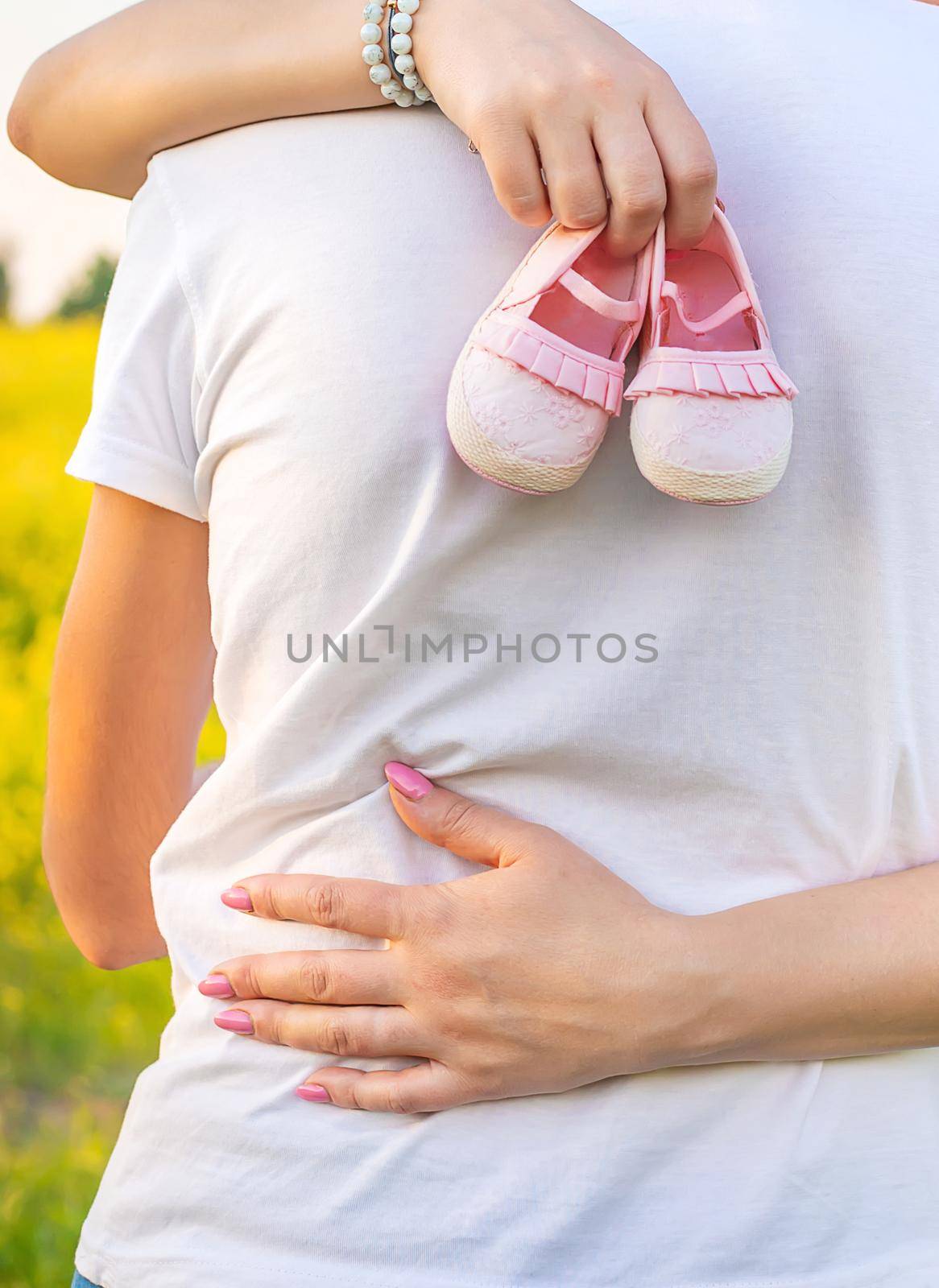 pregnant woman and man hold baby shoes. Selective focus. by yanadjana