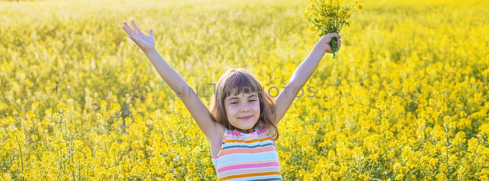 A child in a yellow field, mustard blooms. Selective focus.