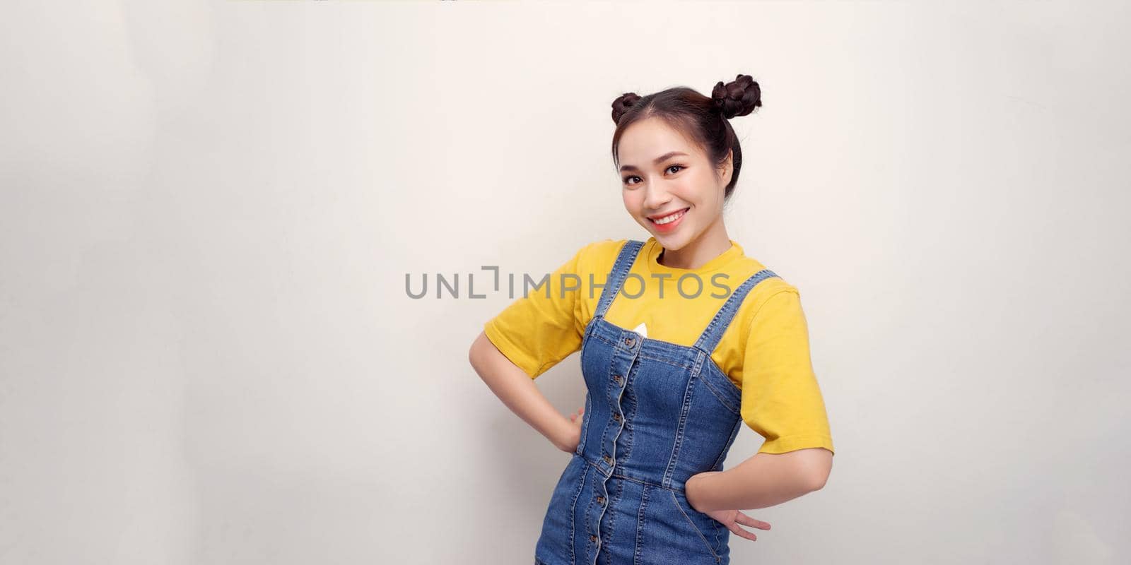 Attractive young woman in casual clothes standing with arms akimbo on waist isolated on  white background in studio.