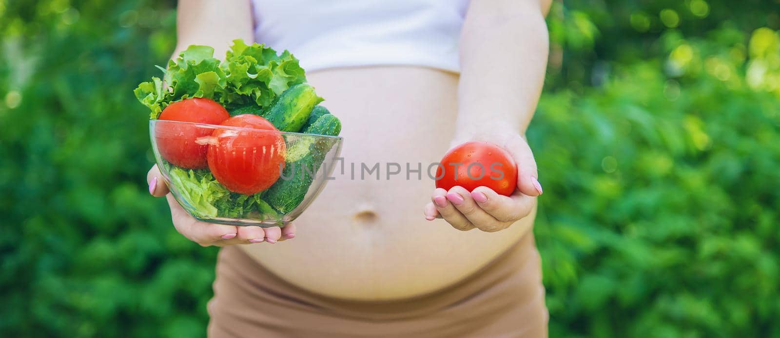 A pregnant woman with vegetables in her hands. Selective focus. by yanadjana