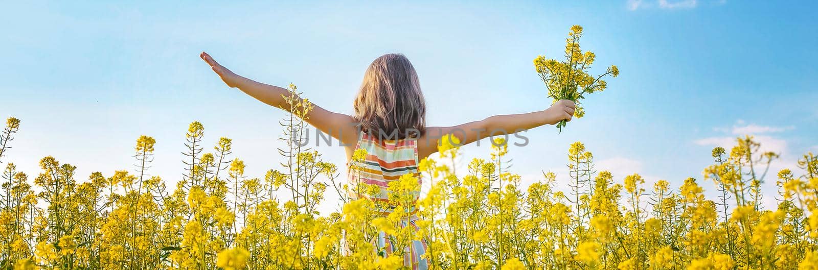 A child in a yellow field, mustard blooms. Selective focus. nature.