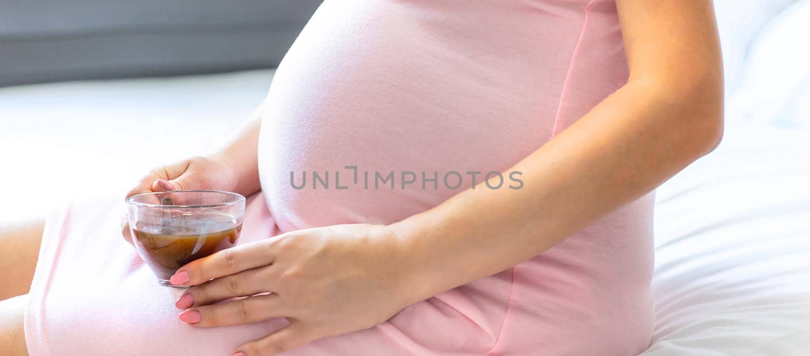 A pregnant woman is drinking coffee. Selective focus. by yanadjana