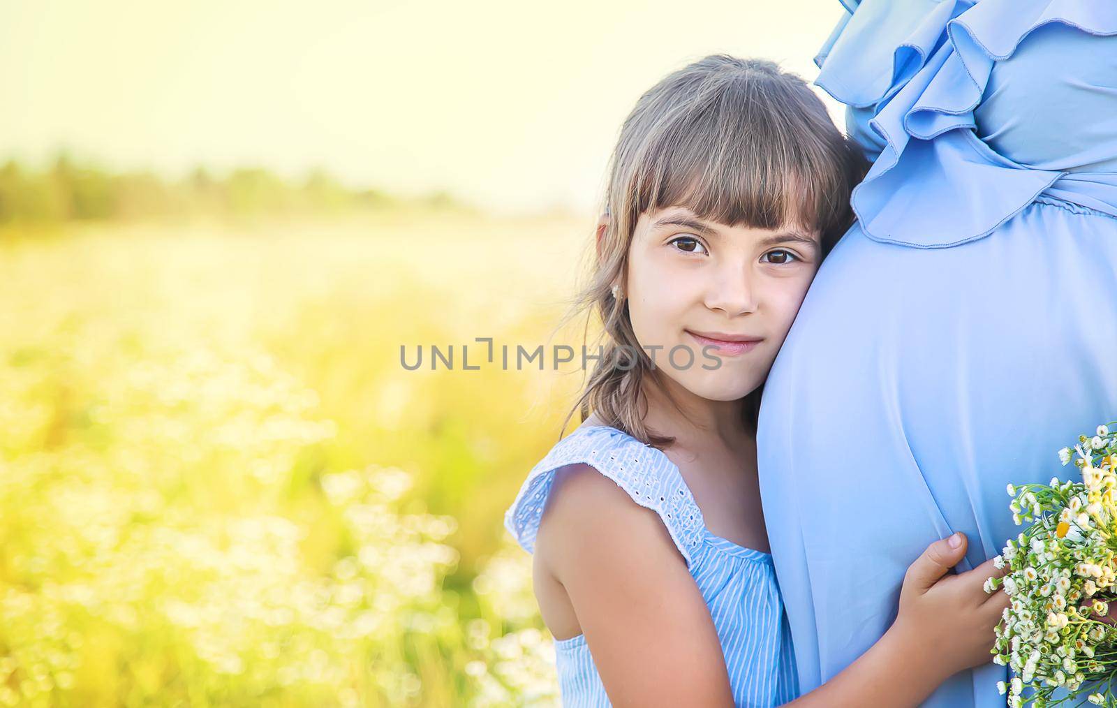pregnant woman with daughter in a field of chamomile. Selective focus.