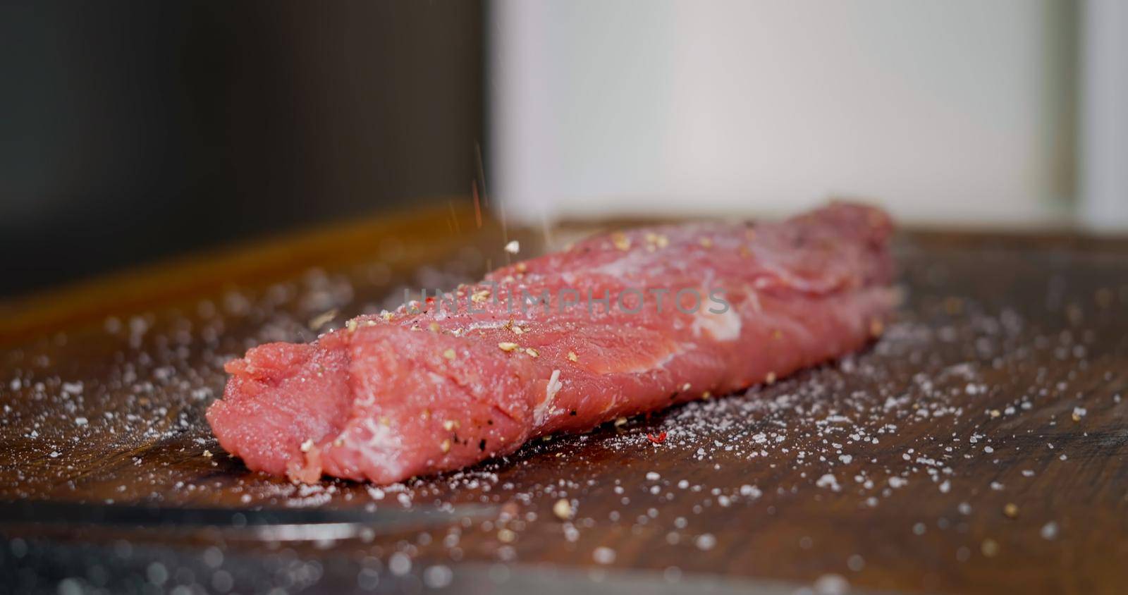 Seasoning Raw Meat on Preparation Table. Chef preparing Meat in Professional Kitchen.