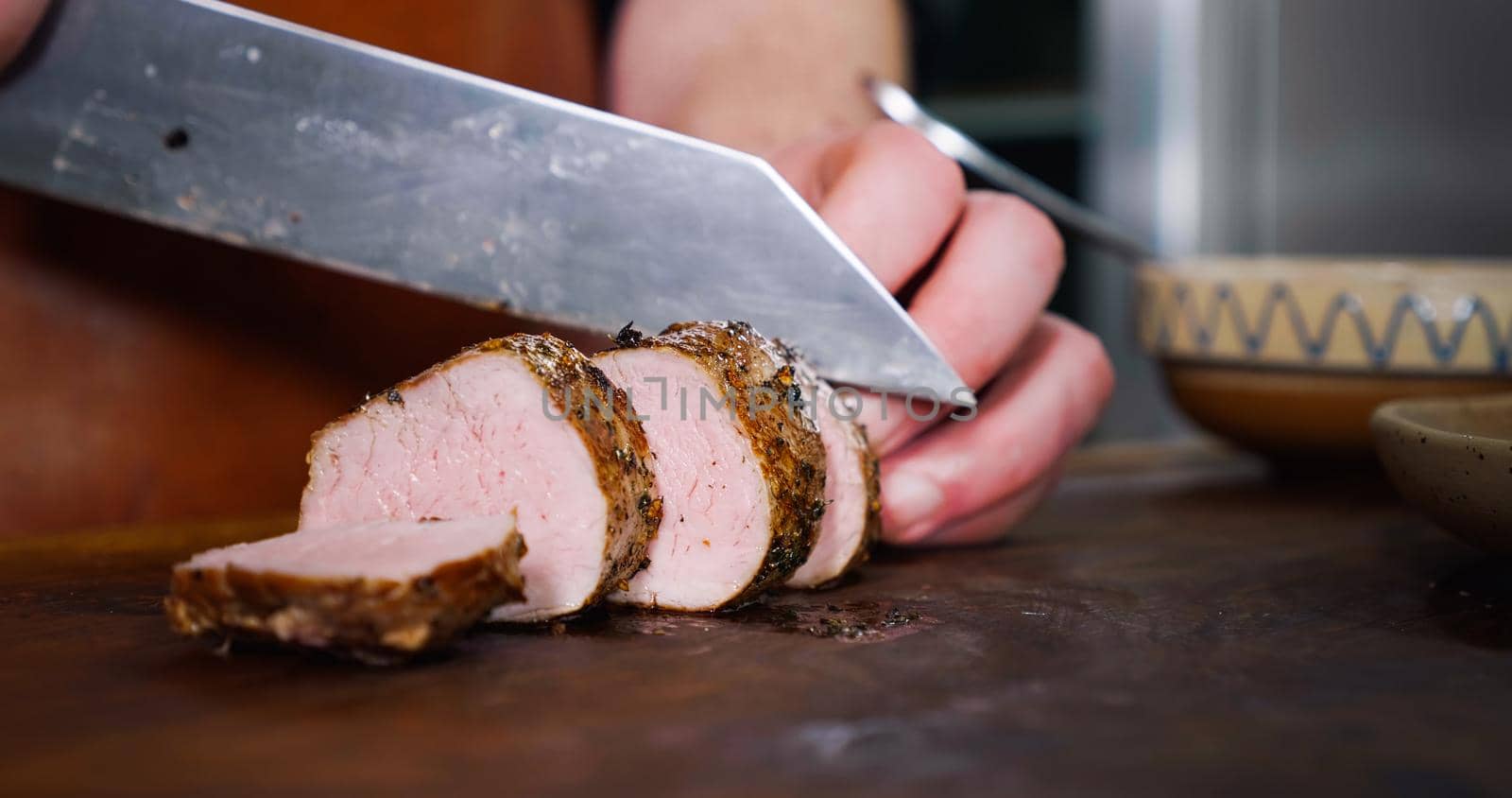 Chef Cuts Juicy Pork Steak on Rustic Cutting Board on Wooden Background. Concept of Delicious Meat Food.