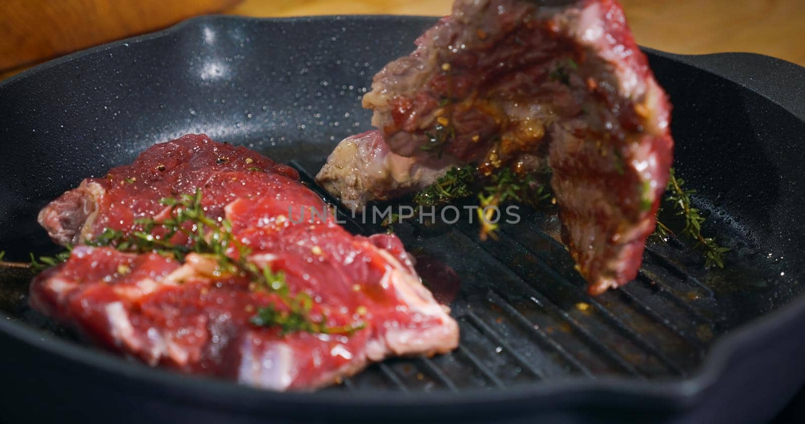 Appetizing Beef Steak cooking in a pan seasoned with herbs. by RecCameraStock