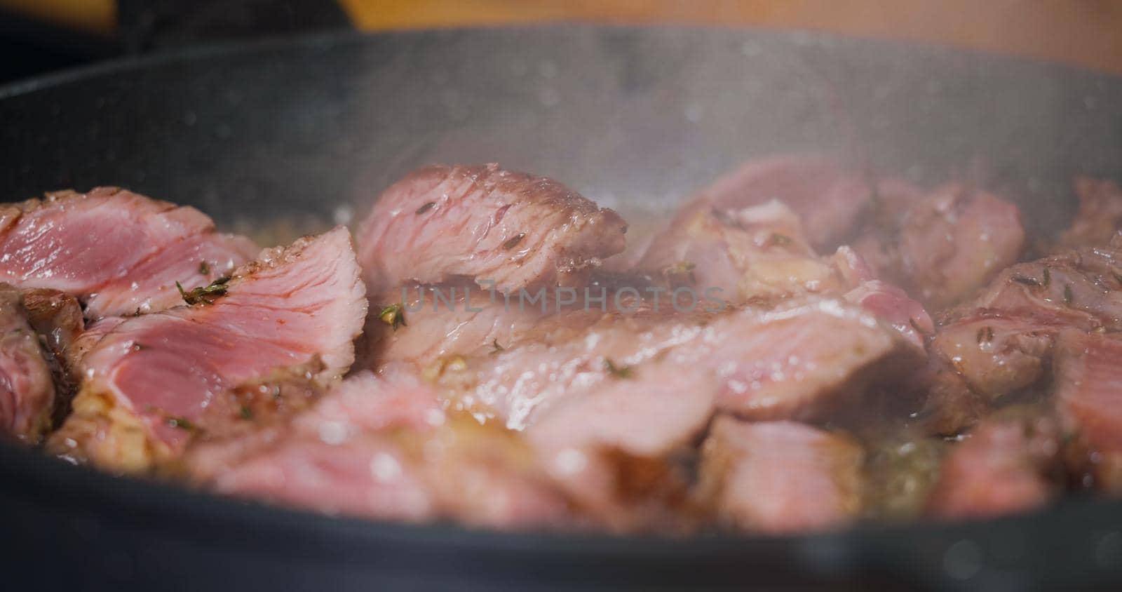 Delicious Juicy Beef Meat Cooking on Pan Seasoned Herbs.