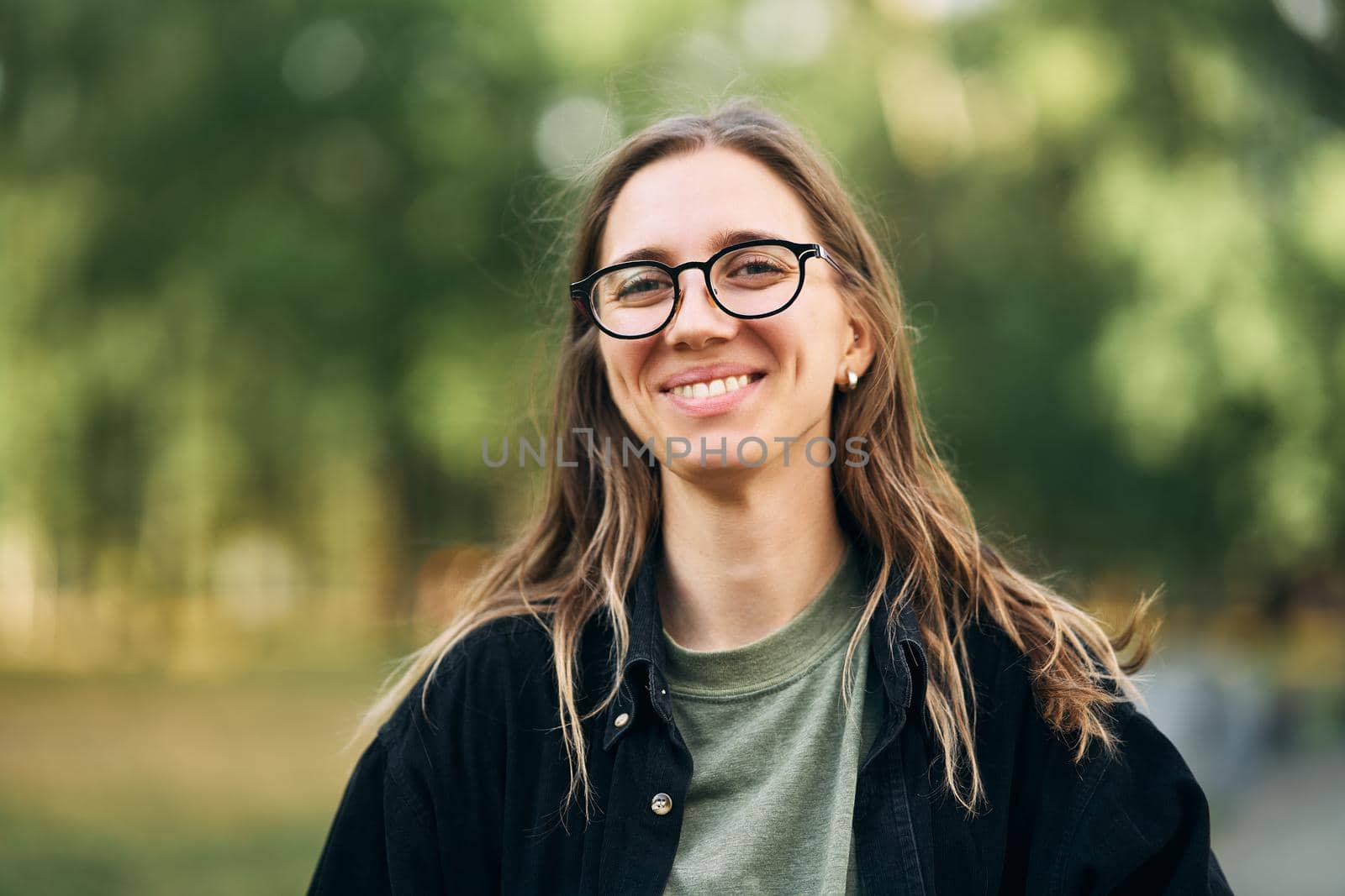 Portrait of a smiling young girl with glasses in the park. High-quality photo