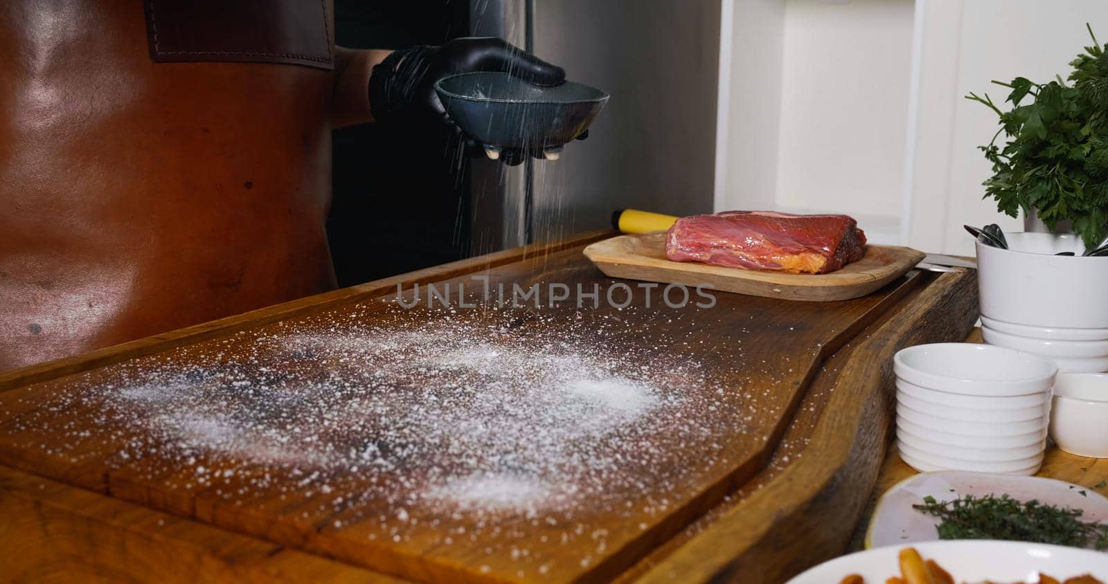 Strewing Salt on Wood Chipper for Fresh Raw Beef Angus Meat. by RecCameraStock