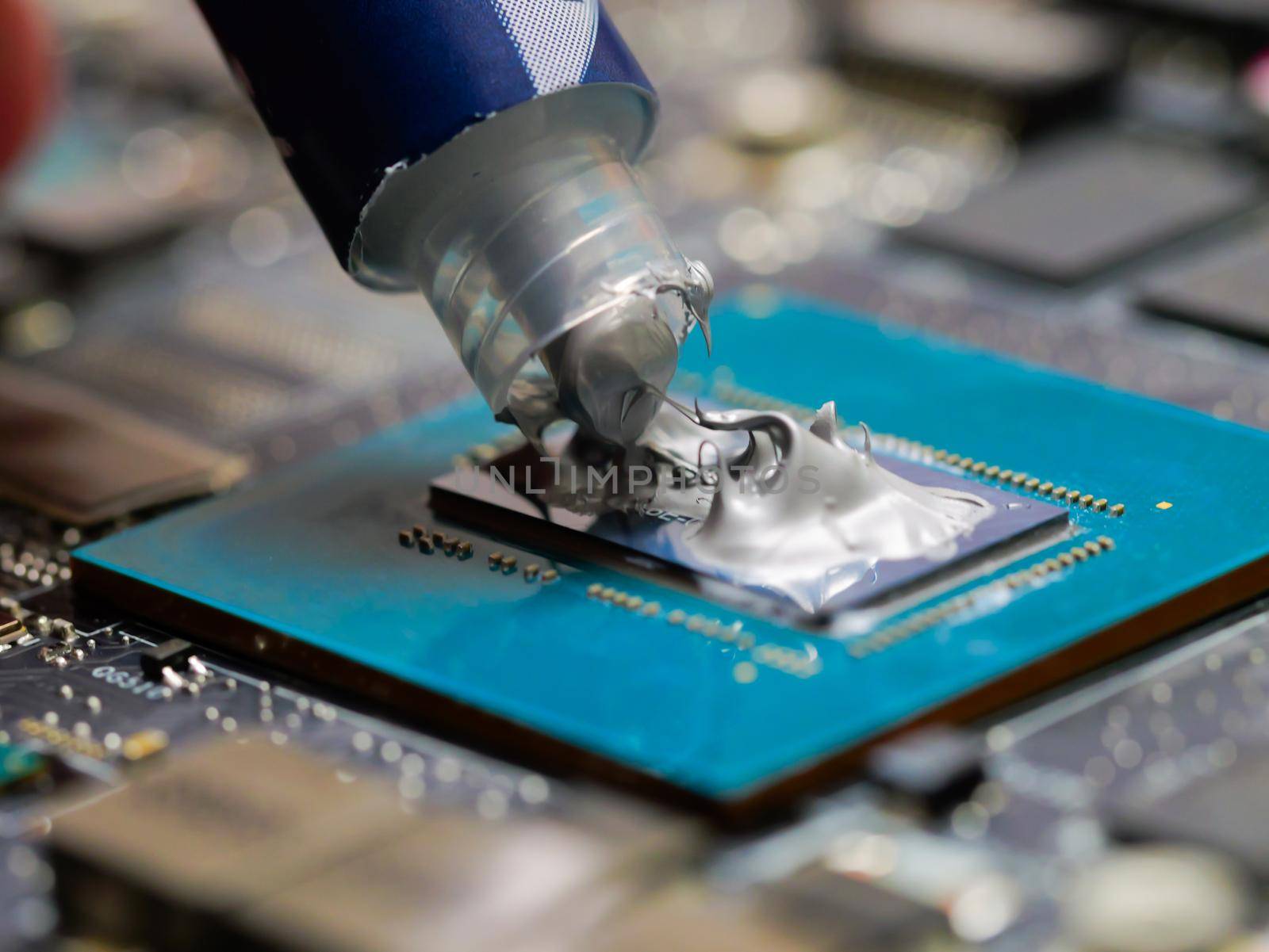 Technician applying thermal paste to a GPU on laptop motherboard. by RecCameraStock